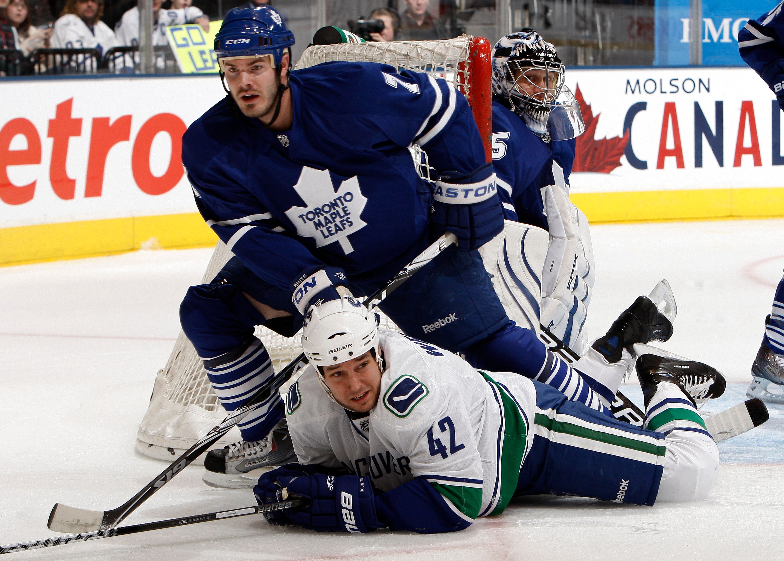 TORONTO - JANUARY 30: Ian White #7 of the Toronto Maple Leafs knocks down Kyle Wellwood #42 of the Vancouver Canucks during game action January 30, 2010 at the Air Canada Centre in Toronto, Ontario, Canada. (Photo by Abelimages / Getty Images)