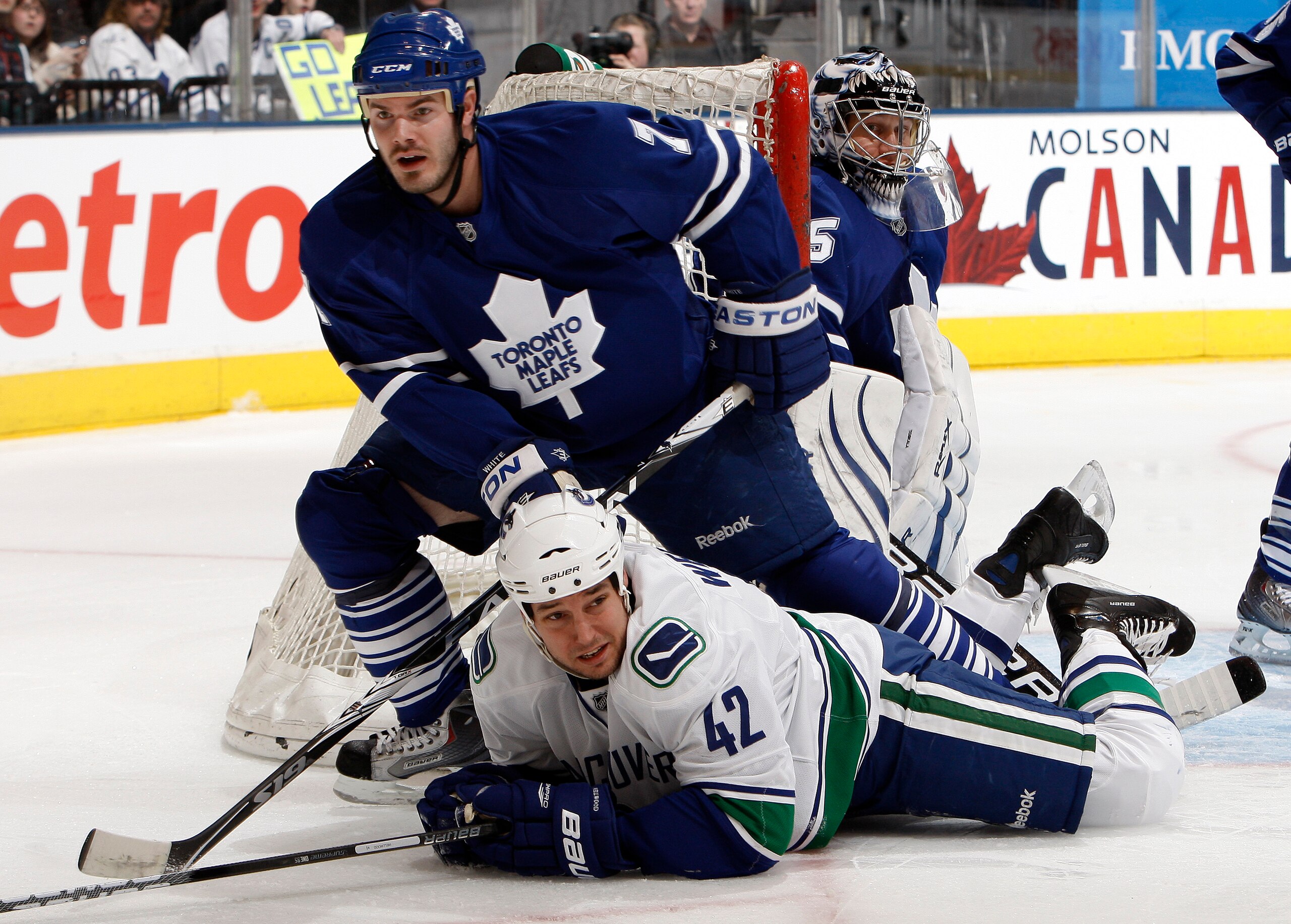 TORONTO - JANUARY 30: Ian White #7 of the Toronto Maple Leafs knocks down Kyle Wellwood #42 of the Vancouver Canucks during game action January 30, 2010 at the Air Canada Centre in Toronto, Ontario, Canada. (Photo by Abelimages / Getty Images)