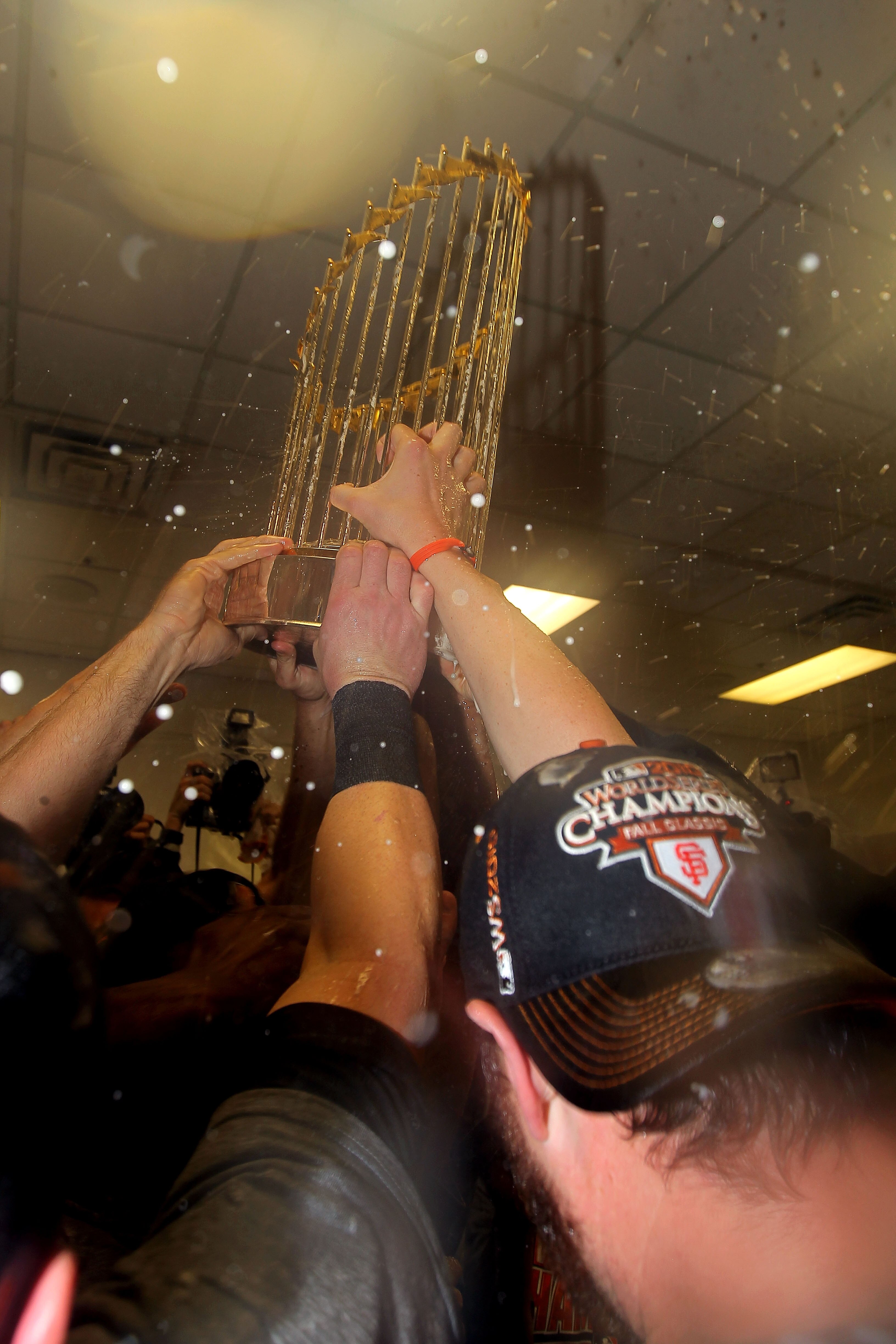 ARLINGTON, TX - NOVEMBER 01:  Players form the San Francisco Giants celebrate with the World Series Championship trophy in the locker room after they won 3-1 against the Texas Rangers in Game Five of the 2010 MLB World Series at Rangers Ballpark in Arling