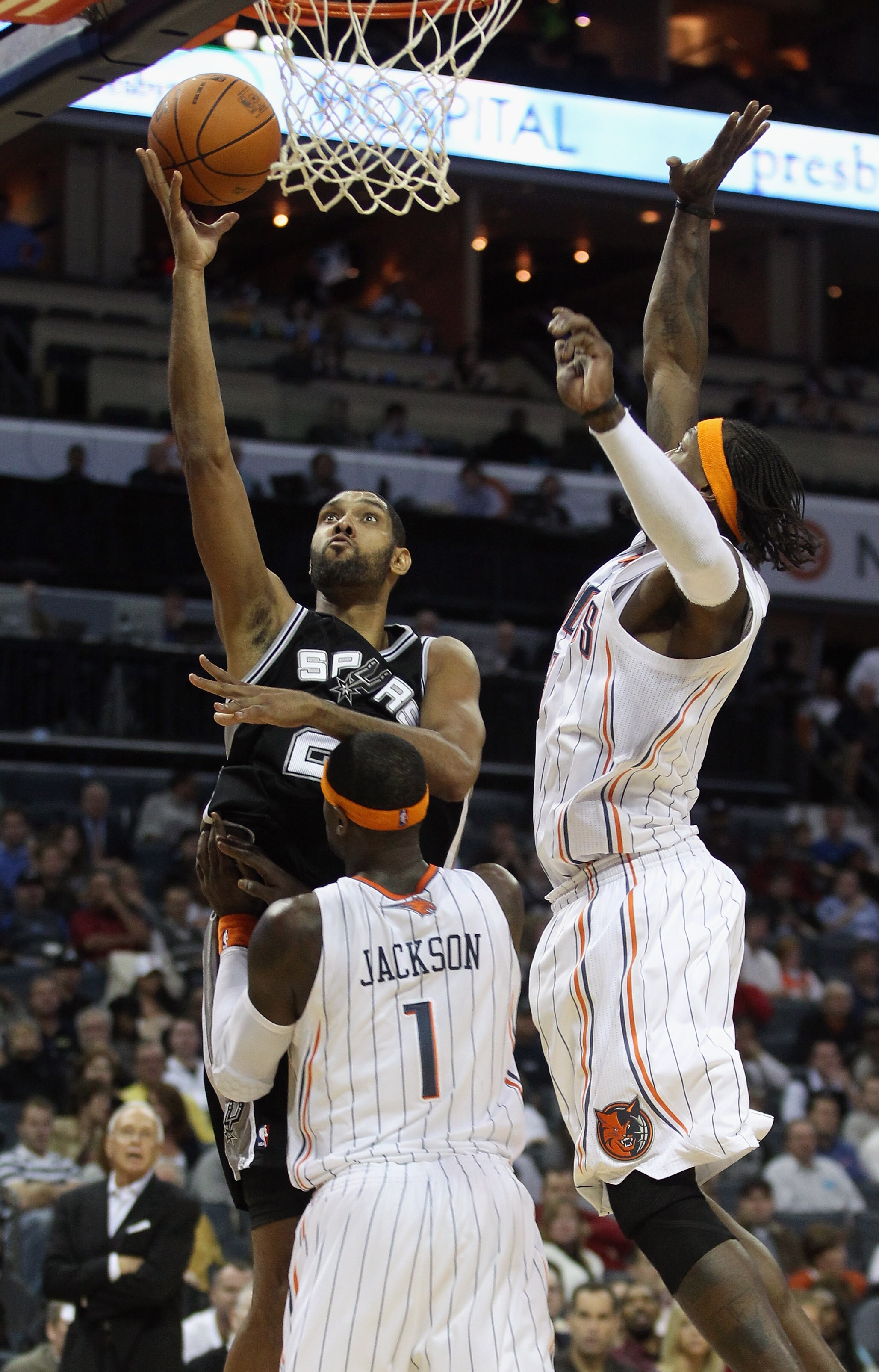 CHARLOTTE, NC - NOVEMBER 08:  Tim Duncan #21 of the San Antonio Spurs shoots over teammates Gerald Wallace #3 and Stephen Jackson #1 of the Charlotte Bobcats during their game at Time Warner Cable Arena on November 8, 2010 in Charlotte, North Carolina.  N
