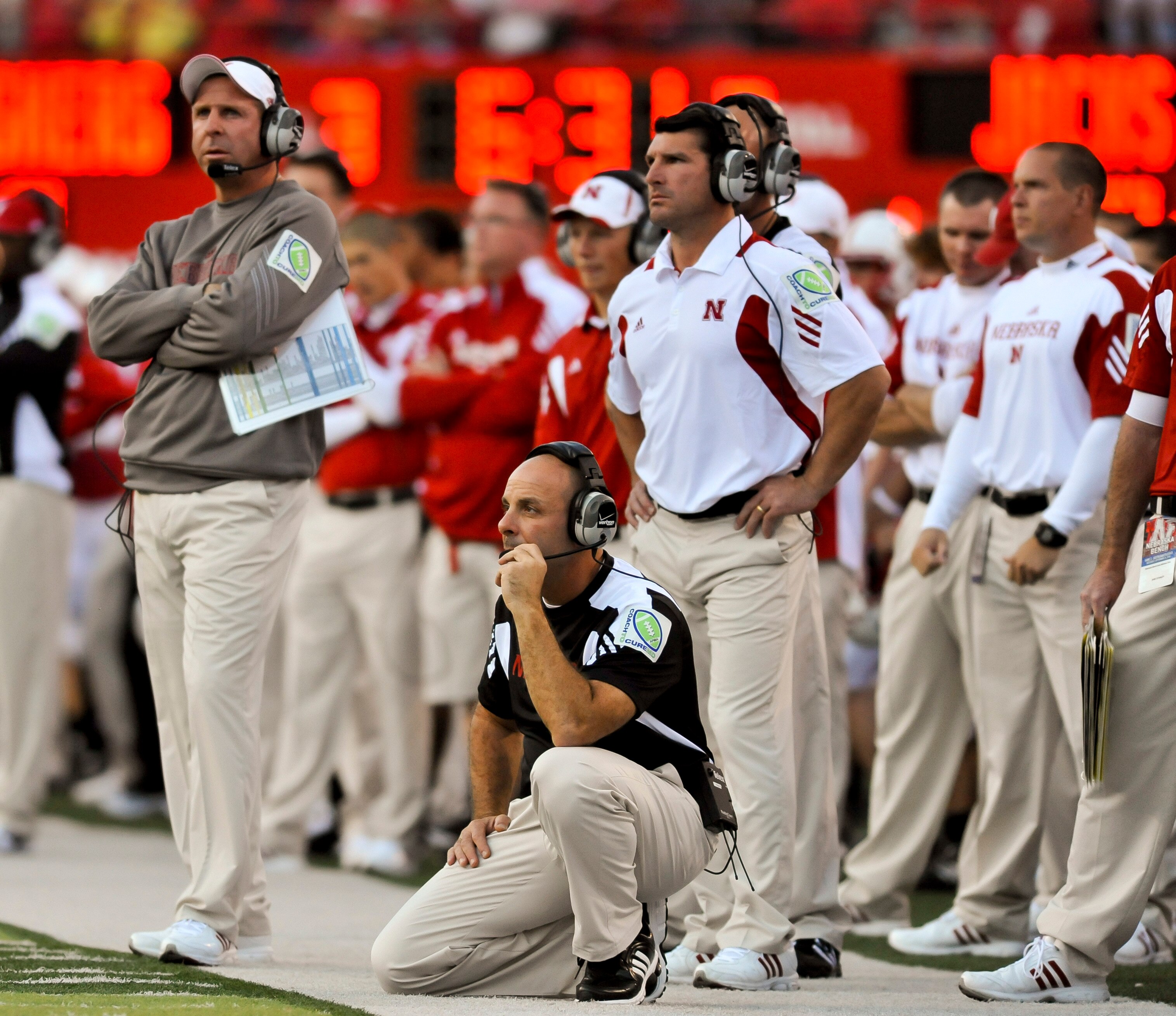 LINCOLN, NEBRASKA - SEPTEMBER 25: Nebraska co-defensive coordinator Carl Pelini (kneeling) and head coach Bo Pelini (L) watch their defense against the South Dakota State Jackrabbits during first half action of their game at Memorial Stadium on September