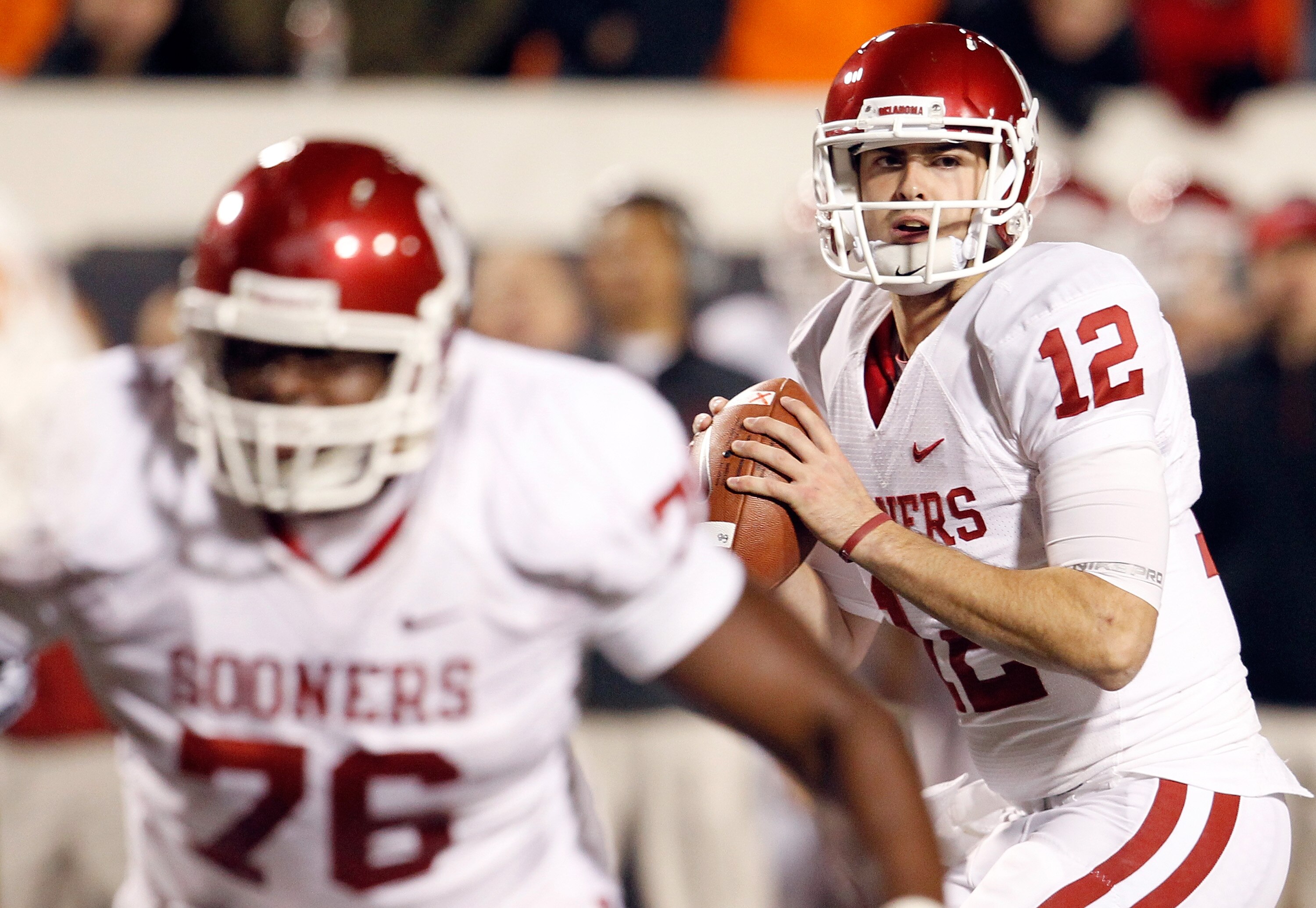 STILLWATER, OK - NOVEMBER 27:  Quarterback Landry Jones #12 of the Oklahoma Sooners looks for an open receiver against the Oklahoma State Cowboys at Boone Pickens Stadium on November 27, 2010 in Stillwater, Oklahoma.  The Sooners beat the Cowboys 47-41. (