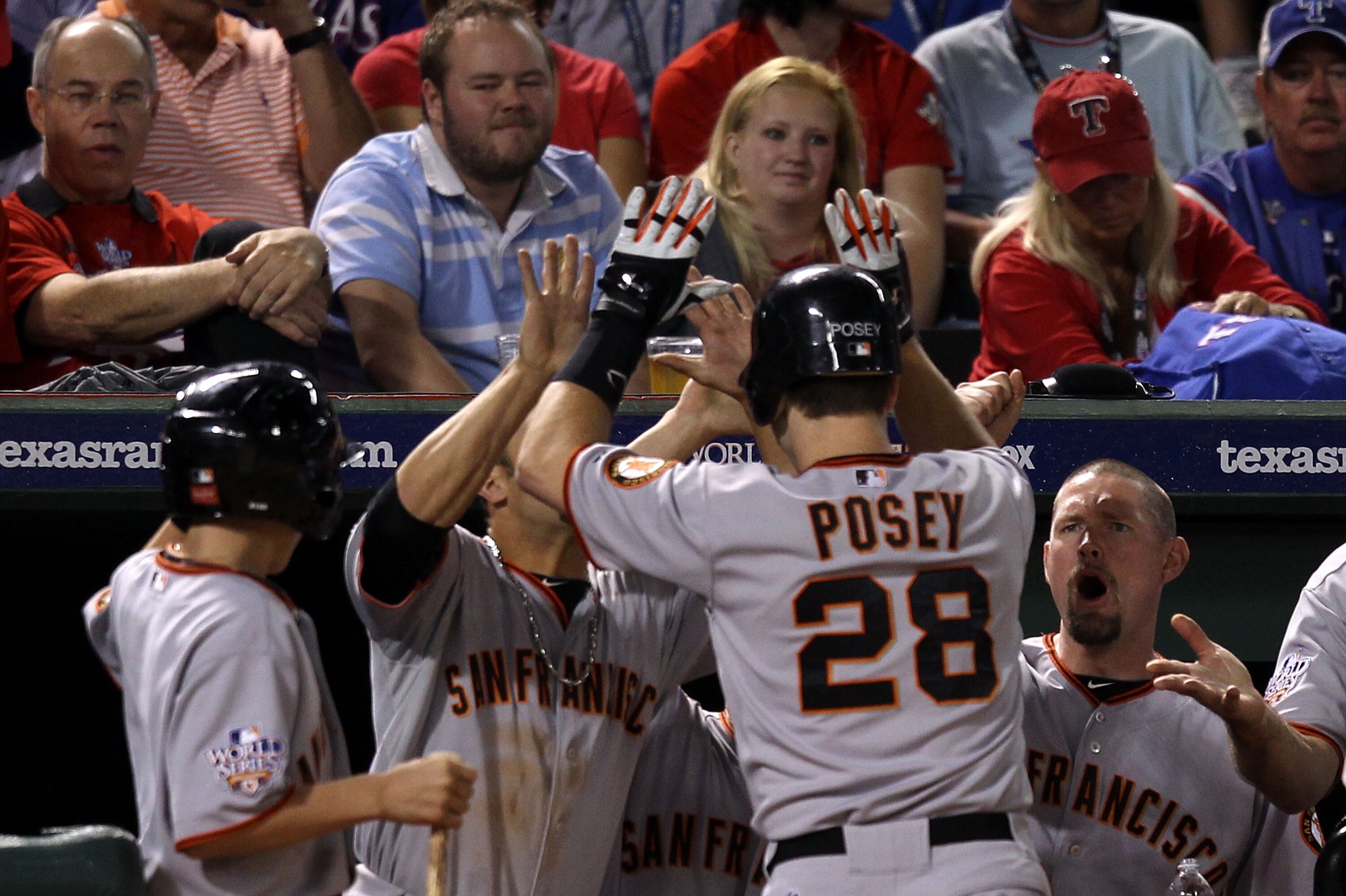 ARLINGTON, TX - OCTOBER 31:  Buster Posey #28 of the San Francisco Giants is congratulated by teammates, including Aubrey Huff #17 (R) for his solo home run in eighth inning as fans of the Texas Rangers look on dejected in Game Four of the 2010 MLB World
