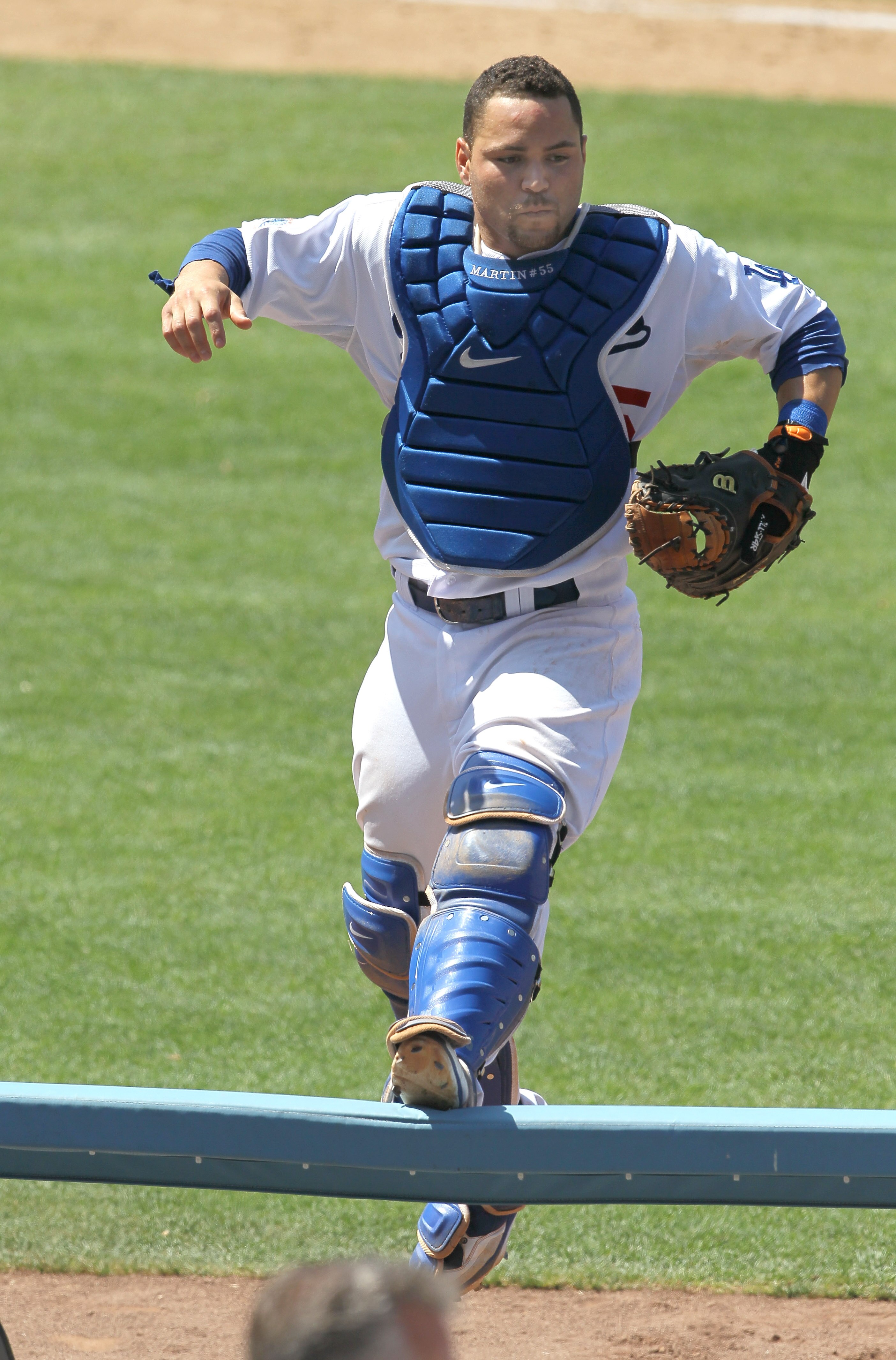 LOS ANGELES - JULY 25:   Catcher Russell Martin #55 of the Los Angeles Dodgers jumps onto a rail beside the New York Mets dugouts as he pursues a pop foul ball that fell into the stands on July 25, 2010 at Dodger Stadium in Los Angeles, California.   The
