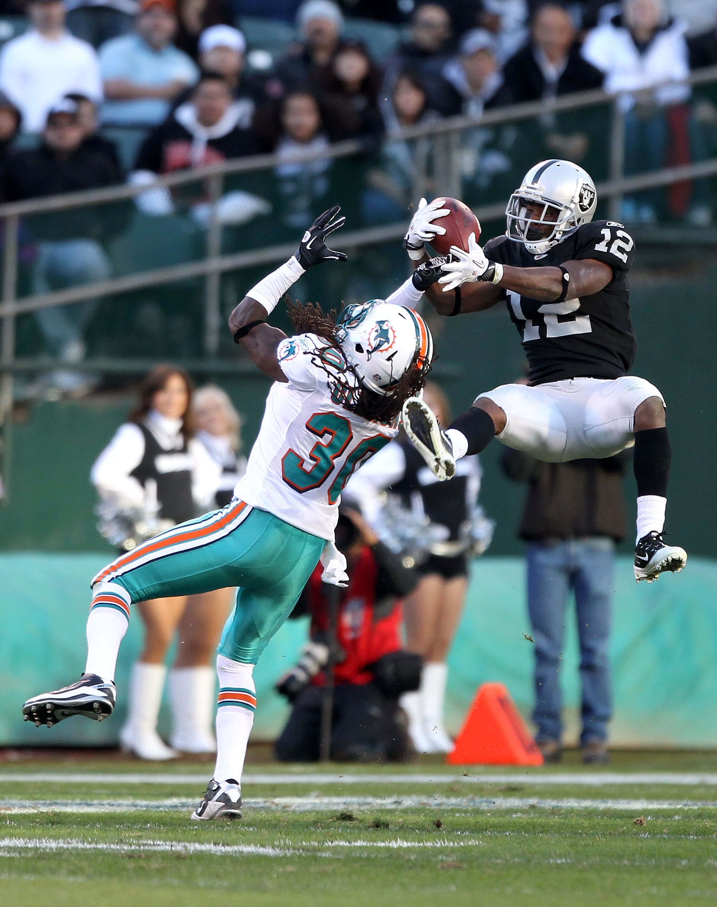 OAKLAND, CA - NOVEMBER 28:  Jacoby Ford #12 of the Oakland Raiders catches the ball while defended by Chris Clemons #30 of the Miami Dolphins at Oakland-Alameda County Coliseum on November 28, 2010 in Oakland, California.  (Photo by Ezra Shaw/Getty Images