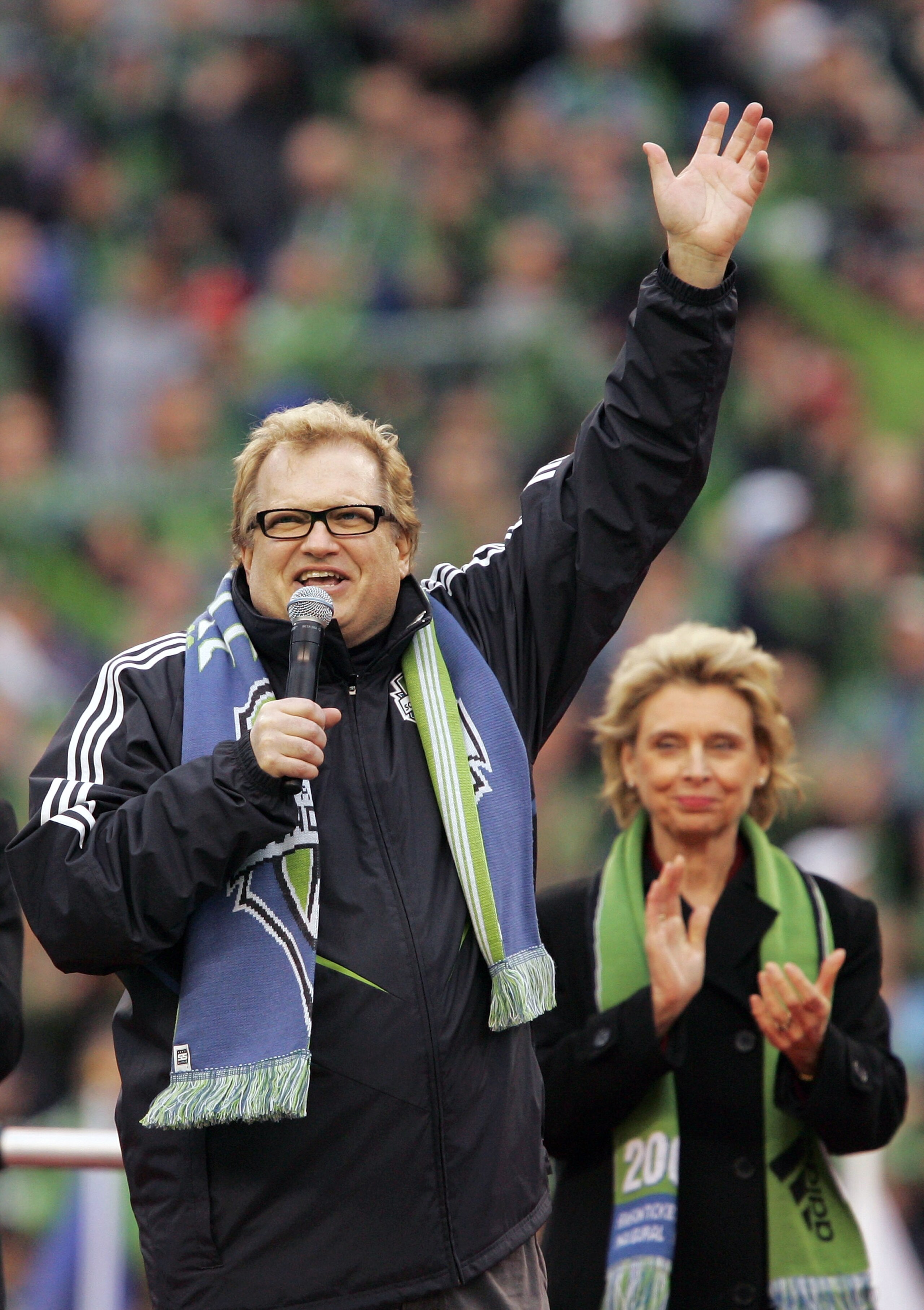 SEATTLE - MARCH 19:  Comedian Drew Carey (L) waves to the crowd as Gov. Christine Gregoire of Washington applauds during pre-game ceremonies for the opening match of the Seattle Sounders FC at Qwest Field March 19, 2009 in Seattle, Washington. The Sounder