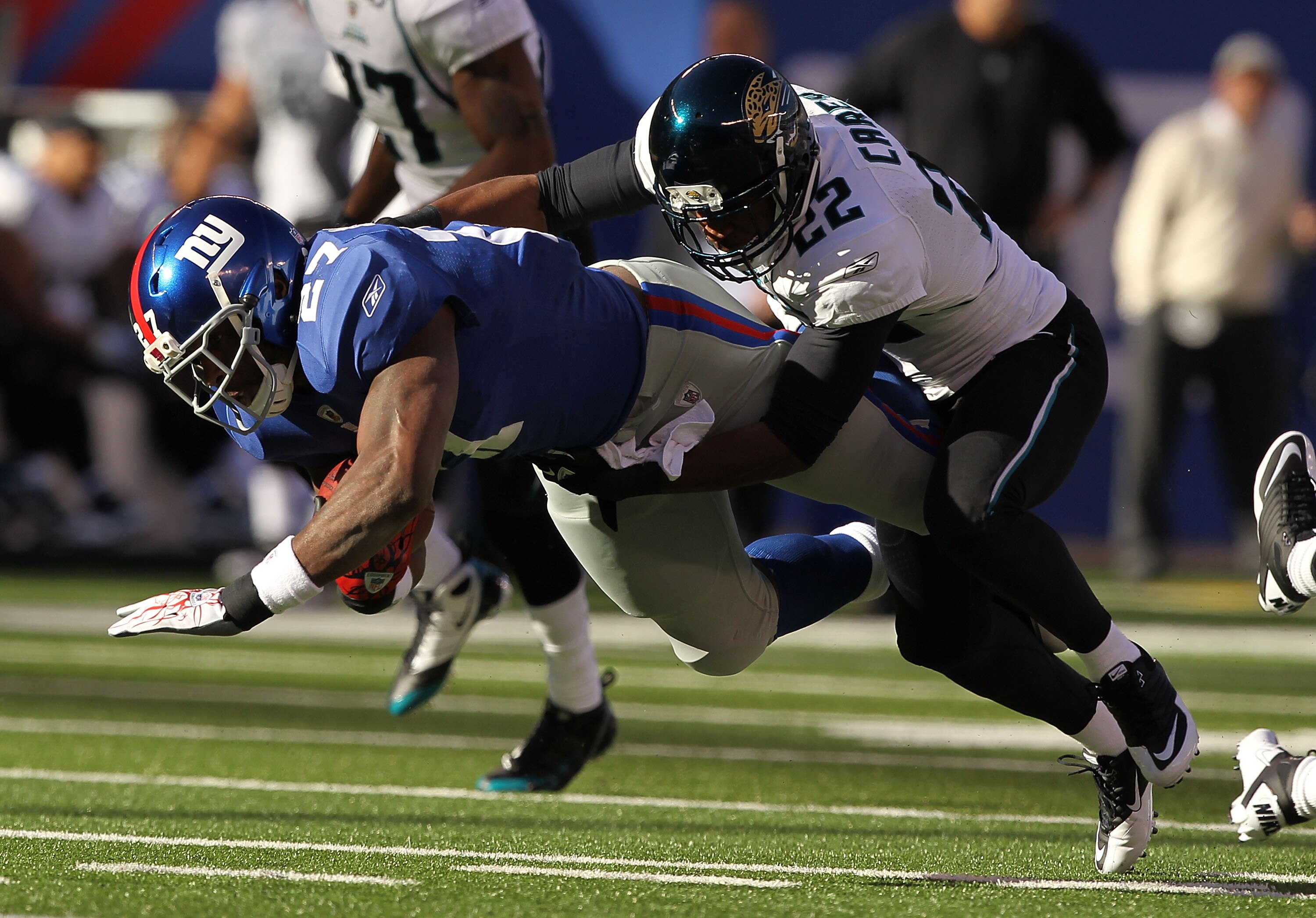 EAST RUTHERFORD, NJ - NOVEMBER 28:  Brandon Jacobs #27 of the New York Giants is tackled by Don Carey #22 of the Jacksonville Jaguars during their game on November 28, 2010 at The New Meadowlands Stadium in East Rutherford, New Jersey.  (Photo by Al Bello