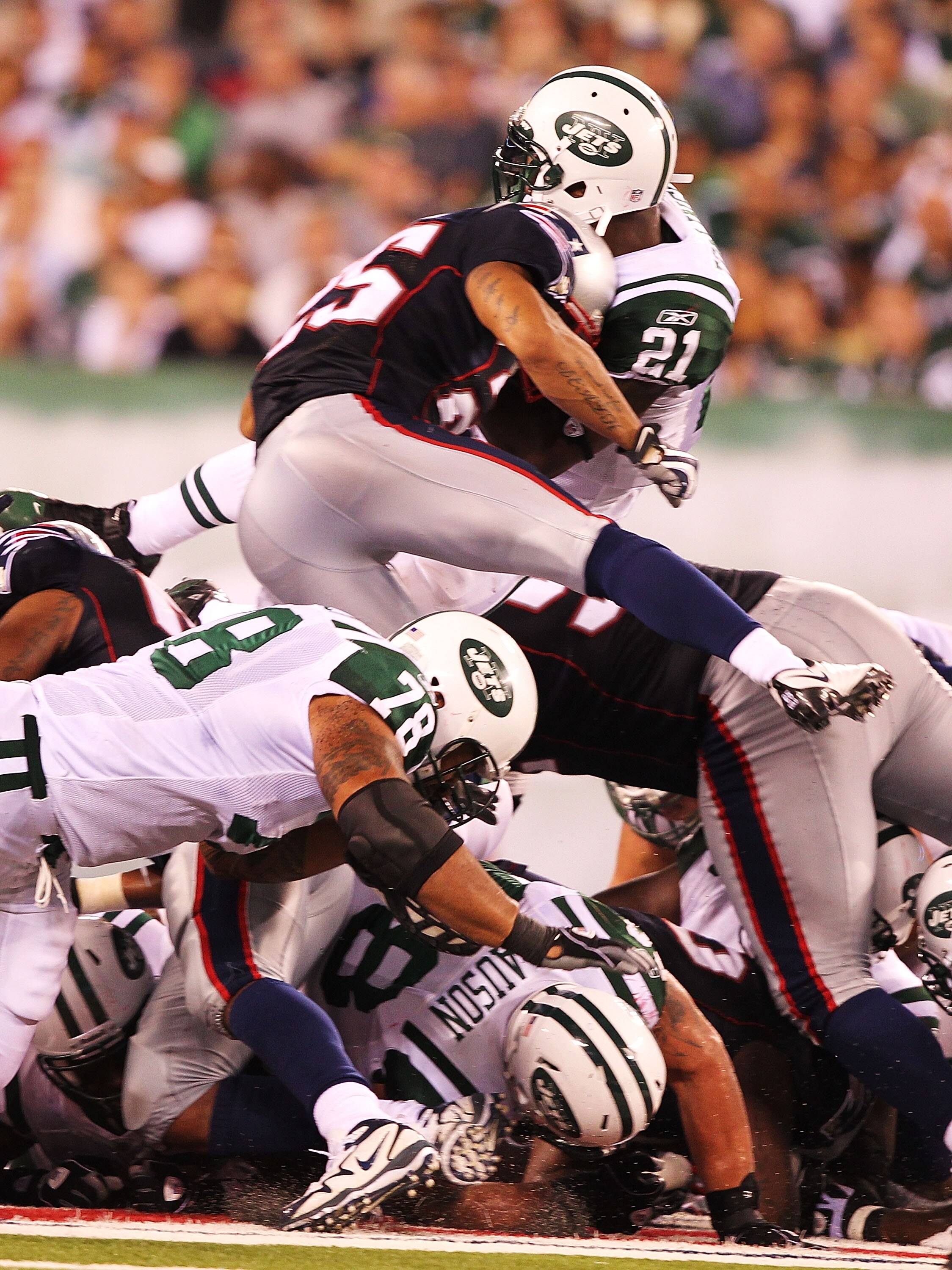 EAST RUTHERFORD, NJ - SEPTEMBER 19:  LaDainian Tomlinson #21  of the New York Jets leaps to a first down in the fourth quarter as Patrick Chung #25  of the New England Patriots delivers the hit during their  game on September 19, 2010 at the New Meadowlan