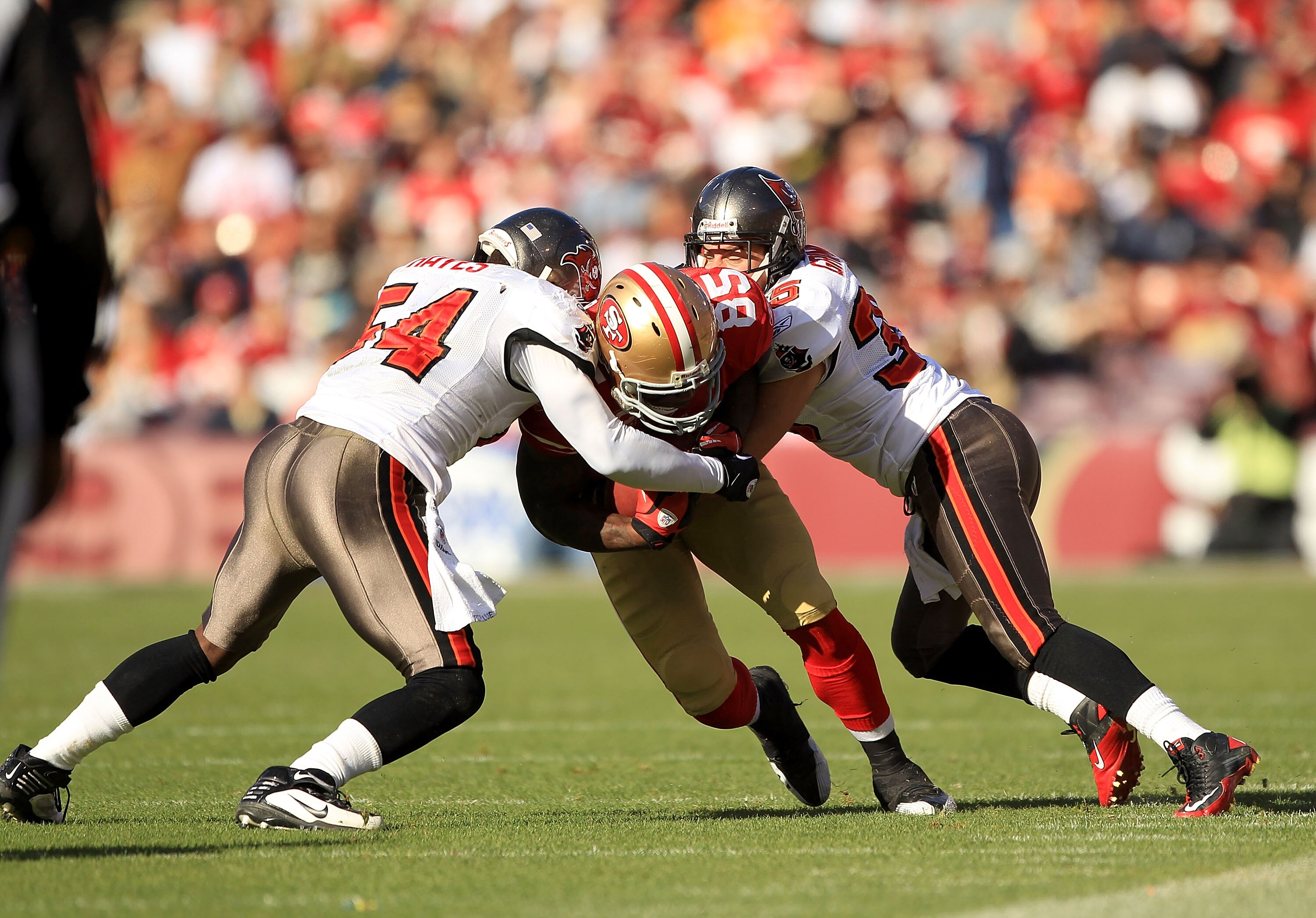 SAN FRANCISCO - NOVEMBER 21:  Vernon Davis #85 of the San Francisco 49ers is tackled by Geno Hayes #54 and Cody Grimm #35 of the Tampa Bay Buccaneers at Candlestick Park on November 21, 2010 in San Francisco, California.  (Photo by Ezra Shaw/Getty Images)