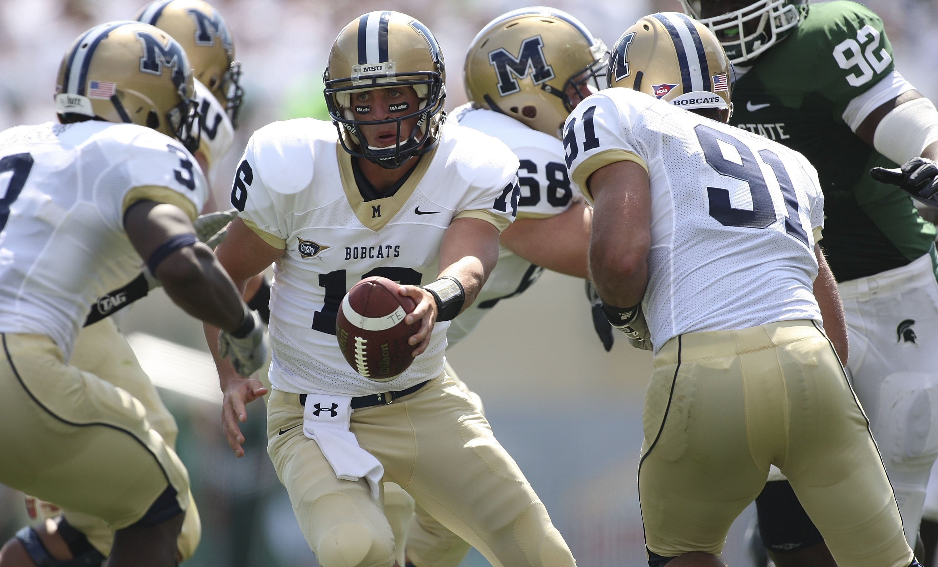 EAST LANSING, MI - SEPTEMBER 05:  Mark Iddins #16 of the Montana State Bobcats hands the ball off to #3 Aaron Mason gainst the Michigan State Spartans in the third quarter on September 5, 2009 at Spartan Stadium in East Lansing, Michigan.  (Photo by Leon