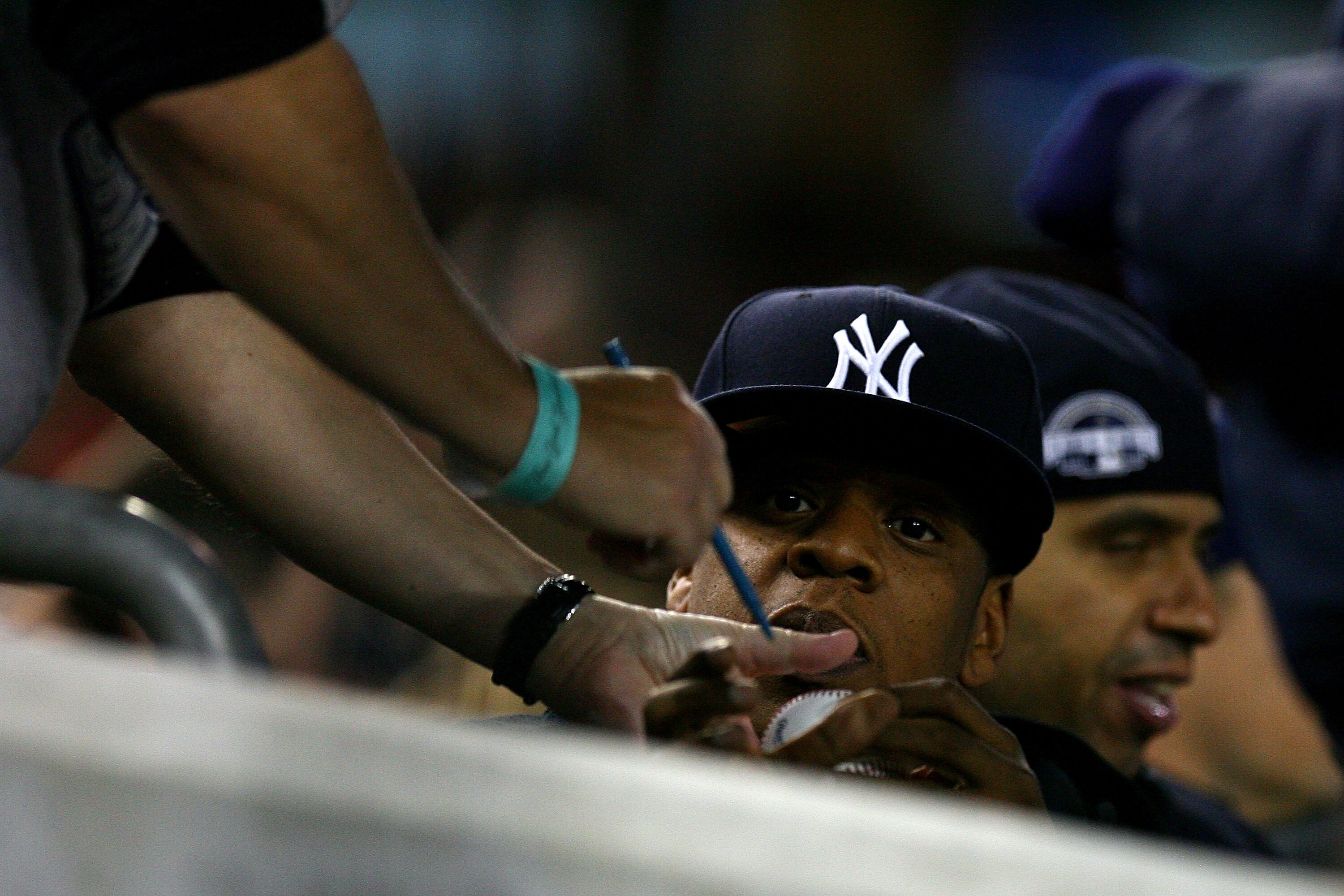 NEW YORK - OCTOBER 19:  Entertainment mogul Jay-Z signs an autograph for a fan while attending Game Four of the ALCS between the New York Yankees and the Texas Rangers during the 2010 MLB Playoffs at Yankee Stadium on October 19, 2010 in the Bronx borough