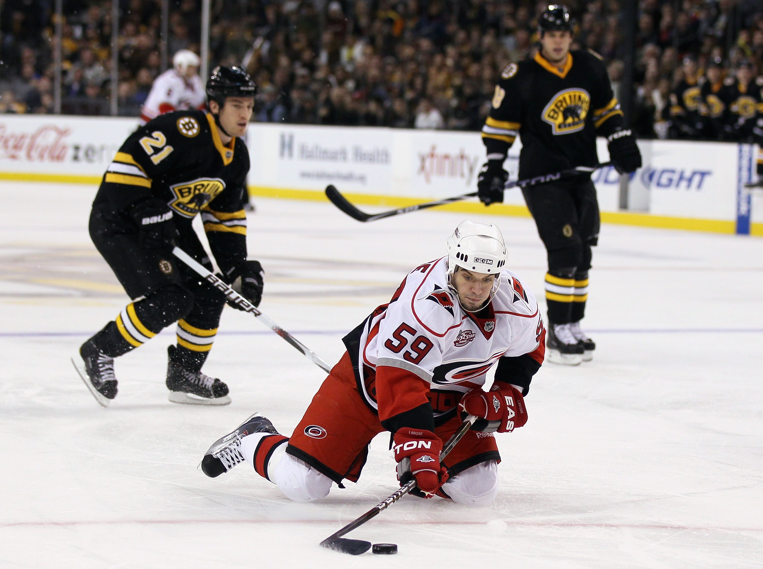 BOSTON - NOVEMBER 26:  Chad LaRose #59 of the Carolina Hurricanes tries to hang on to the puck as Andrew Ference #21 of the Boston Bruins defends on November 26, 2010 at the TD Garden in Boston, Massachusetts.  (Photo by Elsa/Getty Images)