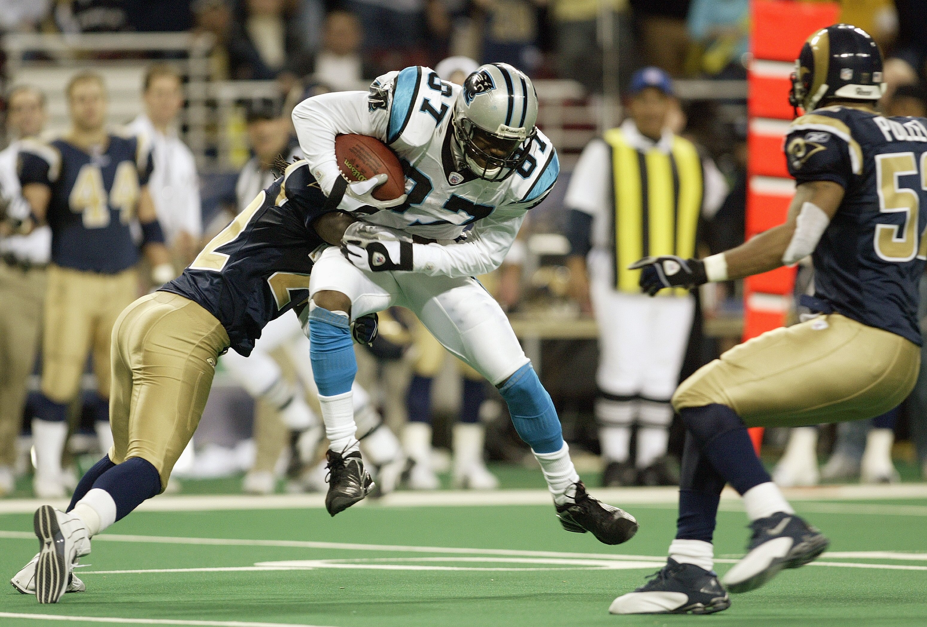 ST. LOUIS - JANUARY10:  Wide receiver Muhsin Muhammad #87 of the Carolina Panthers is hit after making a catch by a St. Louis Rams defensive player during the NFC Divisional Playoff game on January 10, 2004 at the Edward Jones Dome in St. Louis, Missouri.