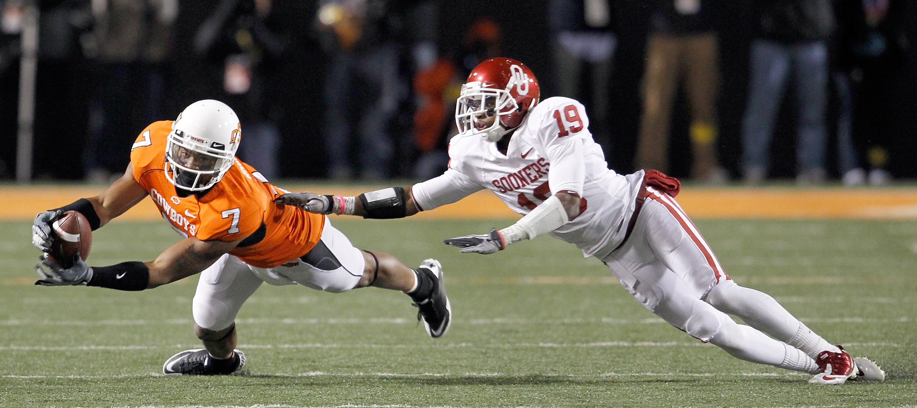 STILLWATER, OK - NOVEMBER 27:  Receiver Michael Harrison #7 of the Oklahoma State Cowboys pulls in a pass against defensive back Demontre Hurst #19 of the Oklahoma Sooners at Boone Pickens Stadium on November 27, 2010 in Stillwater, Oklahoma.  The Sooners