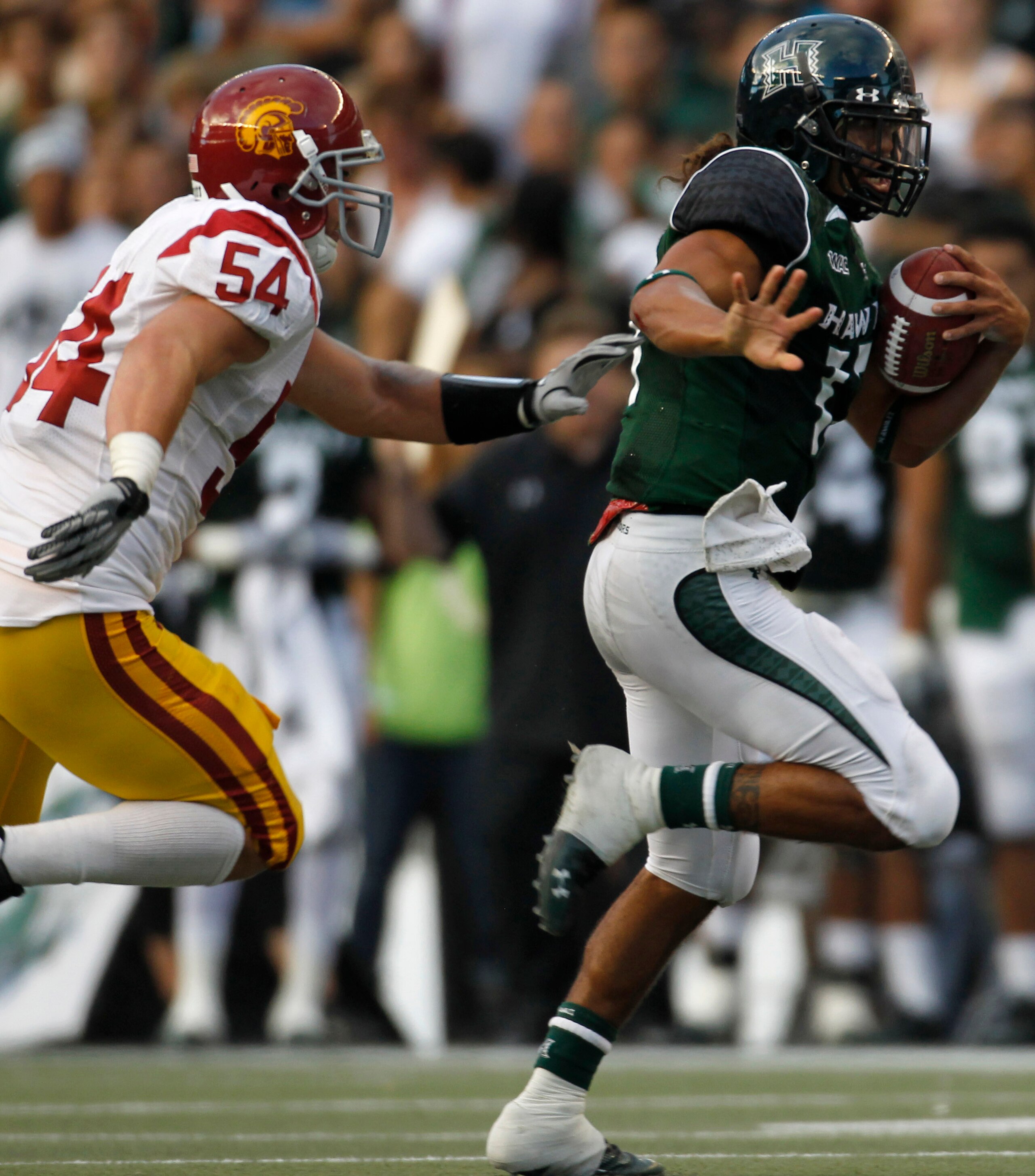 HONOLULU - SEPTEMBER 02: Quarterback Bryant Moniz #17 of the University of Hawaii Warriors is chased by Chris Galippo #54 of the University of Southern California Trojans as he carries the ball during first half action against the University of Southern C