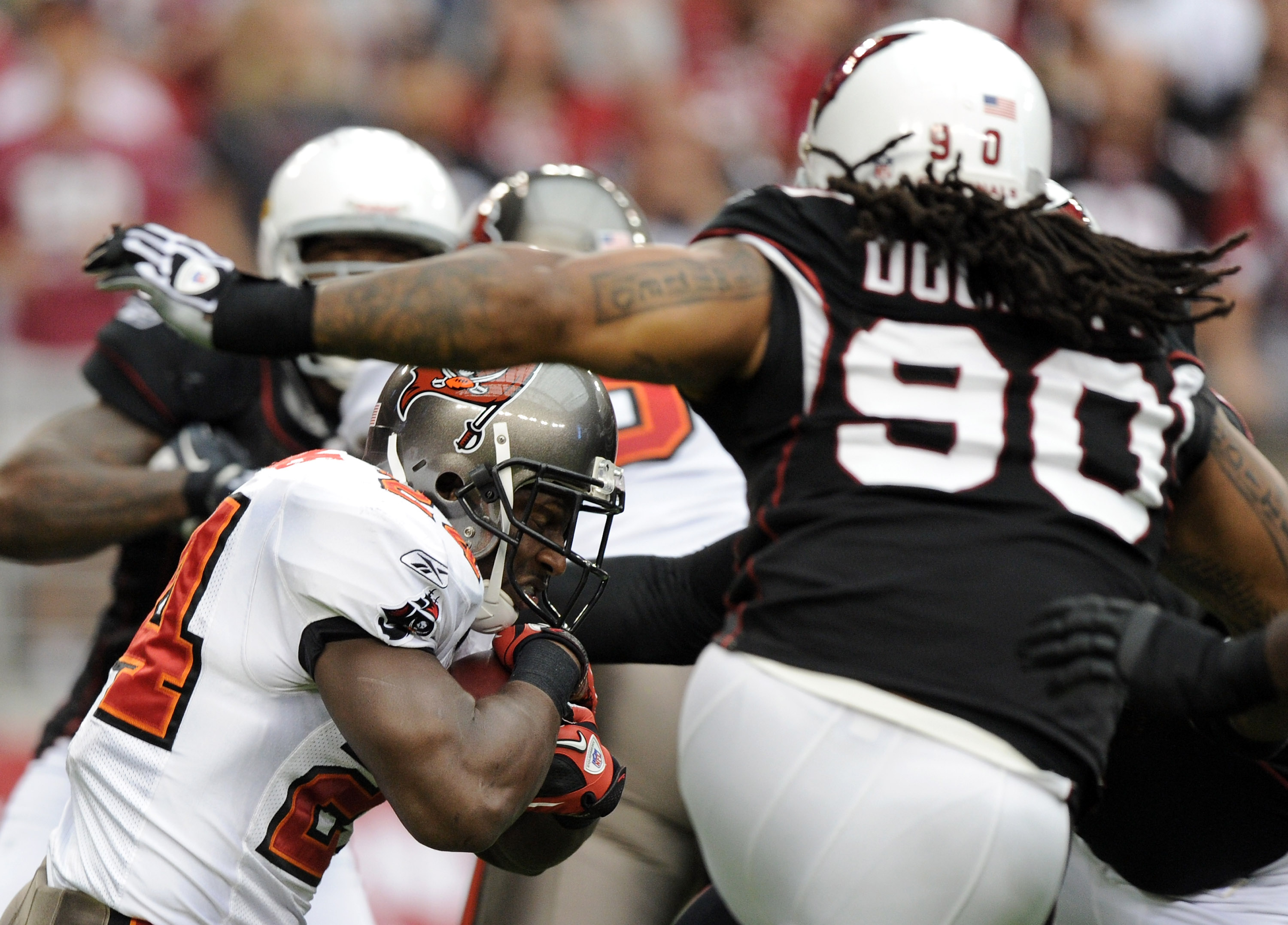 GLENDALE, AZ - OCTOBER 31:  Carnell Williams #24 of the Tampa Bay Buccaneers attempts to duck the tackle of Darnell Dockett #90 of the Arizona Cardinals at University of Phoenix Stadium on October 31, 2010 in Glendale, Arizona.  (Photo by Harry How/Getty