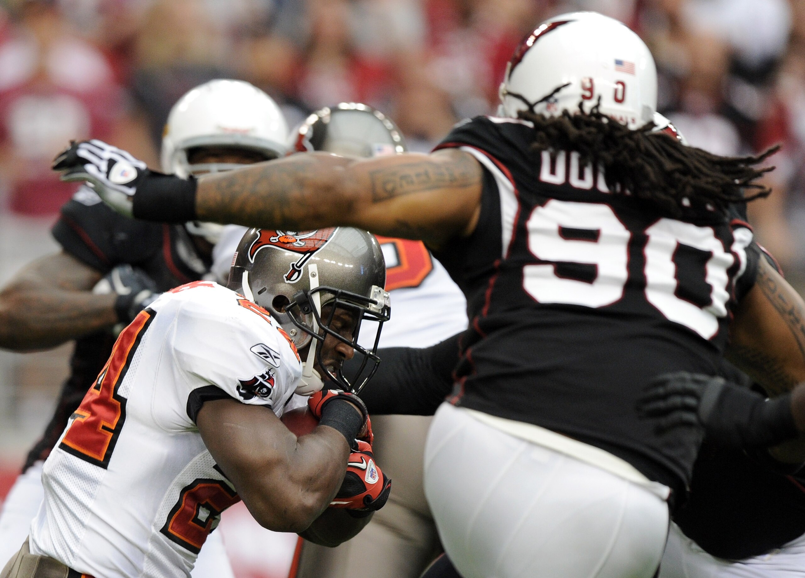 GLENDALE, AZ - OCTOBER 31:  Carnell Williams #24 of the Tampa Bay Buccaneers attempts to duck the tackle of Darnell Dockett #90 of the Arizona Cardinals at University of Phoenix Stadium on October 31, 2010 in Glendale, Arizona.  (Photo by Harry How/Getty