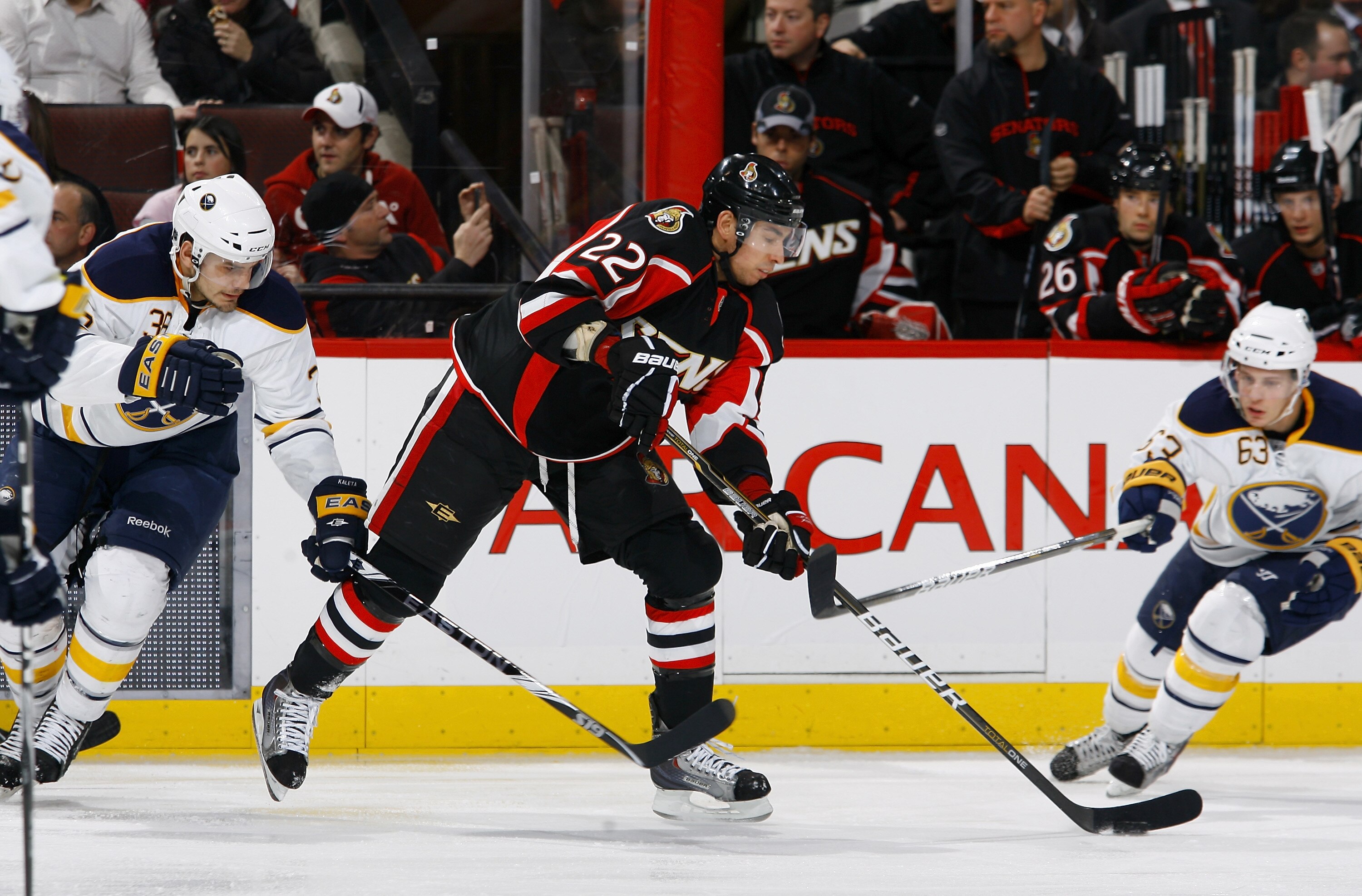 OTTAWA, ON - DECEMBER 04:  Chris Kelly #22 of the Ottawa Senators dekes between Patrick Kaleta #36 and Tyler Ennis #63 of the Buffalo Sabres in a game at Scotiabank Place on December 4, 2010 in Ottawa, Ontario, Canada.  (Photo by Phillip MacCallum/Getty I