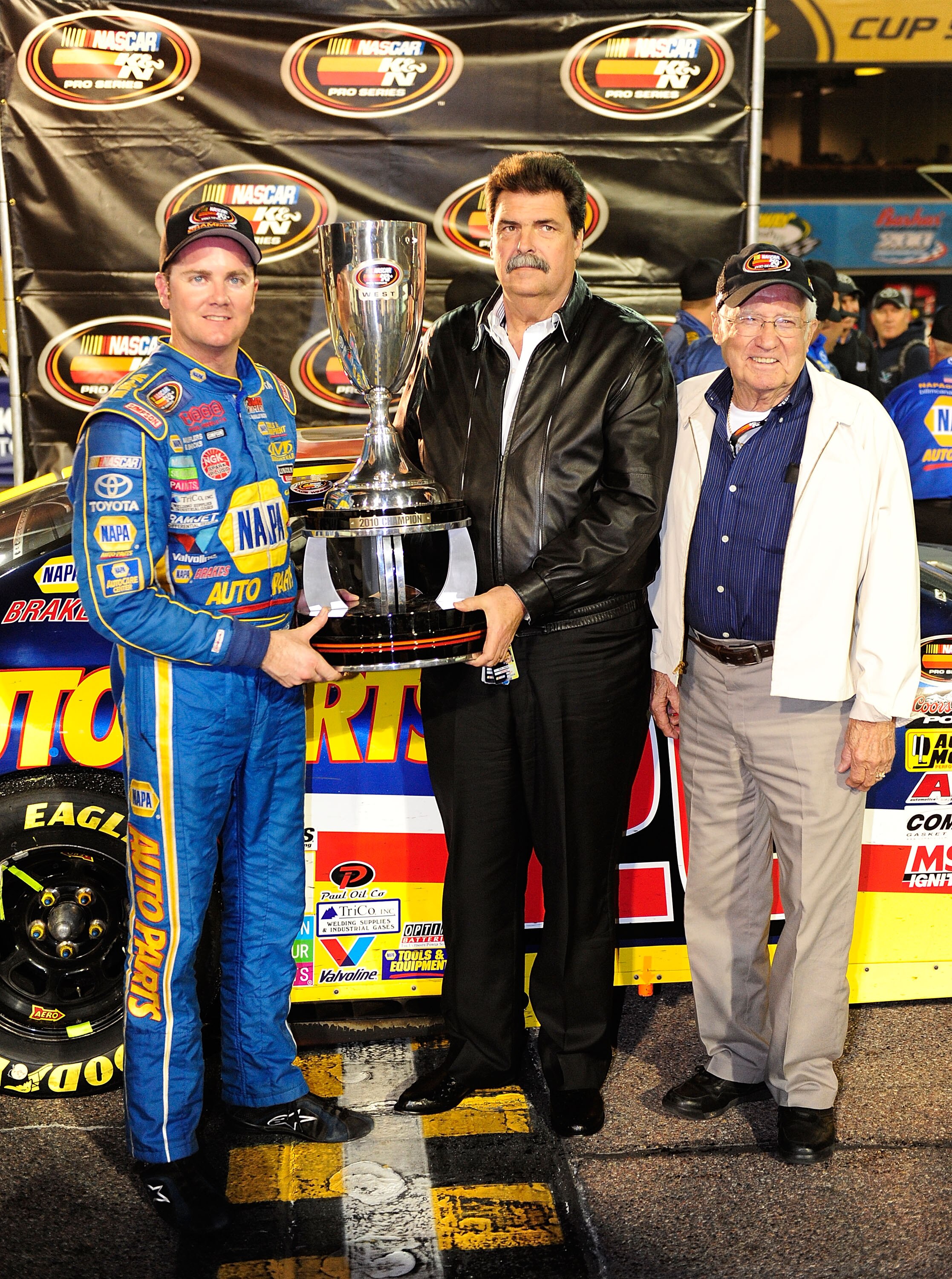 AVONDALE, AZ - NOVEMBER 13:  Eric Holmes #20 (L) celebrates winning the NASCAR K&N Pro Series championship with NASCAR President Mike Helton (C) following the 3 Amigos Tequila 125 at Phoenix International Raceway on November 13, 2010 in Avondale, Arizona.