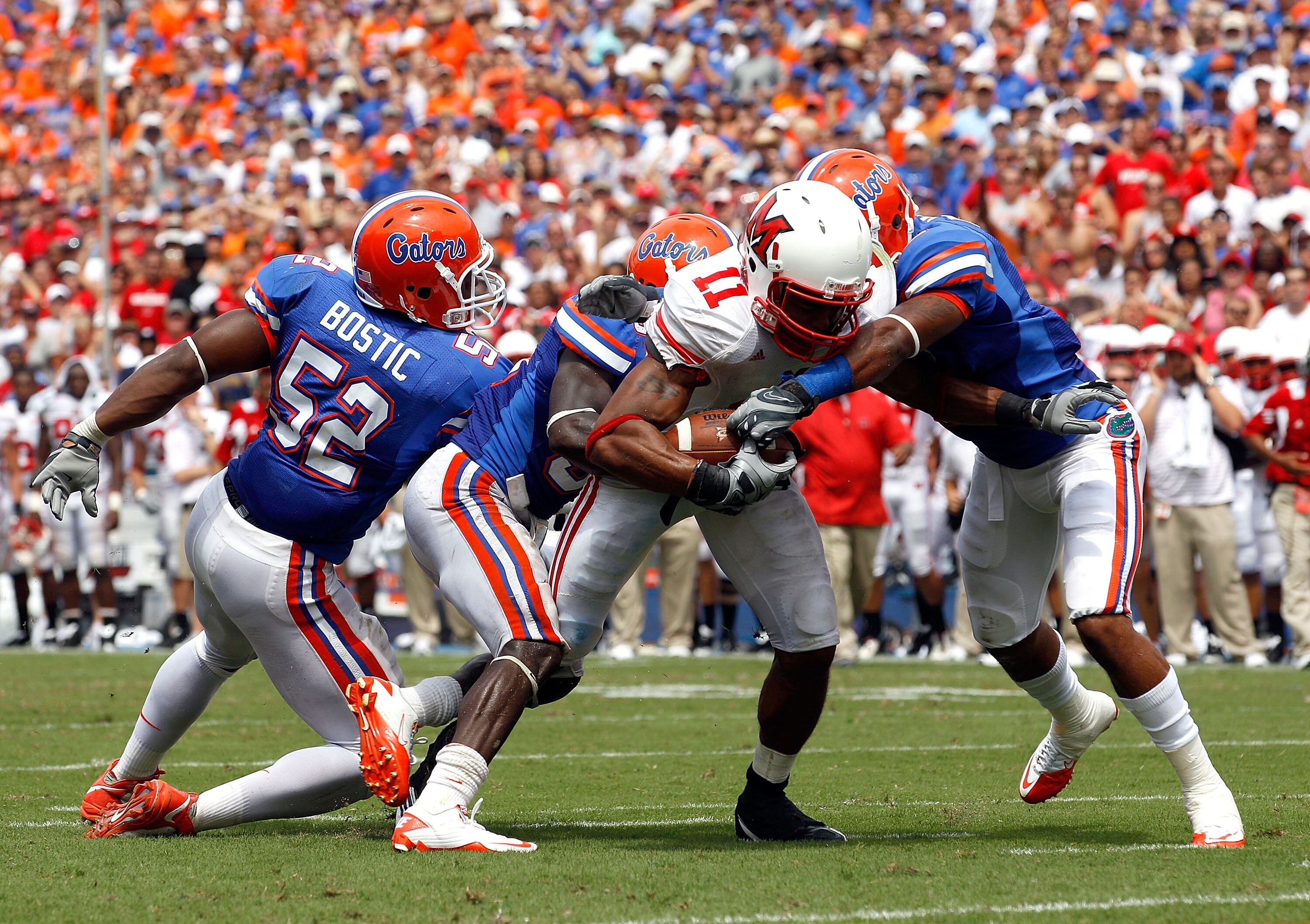 GAINESVILLE, FL - SEPTEMBER 04:  Armand Robinson #11 of the Miami University RedHawks is tackled by Johnathan Bostic #52 and Jeremy Brown #8 of the Florida Gators at Ben Hill Griffin Stadium on September 4, 2010 in Gainesville, Florida.  (Photo by Sam Gre