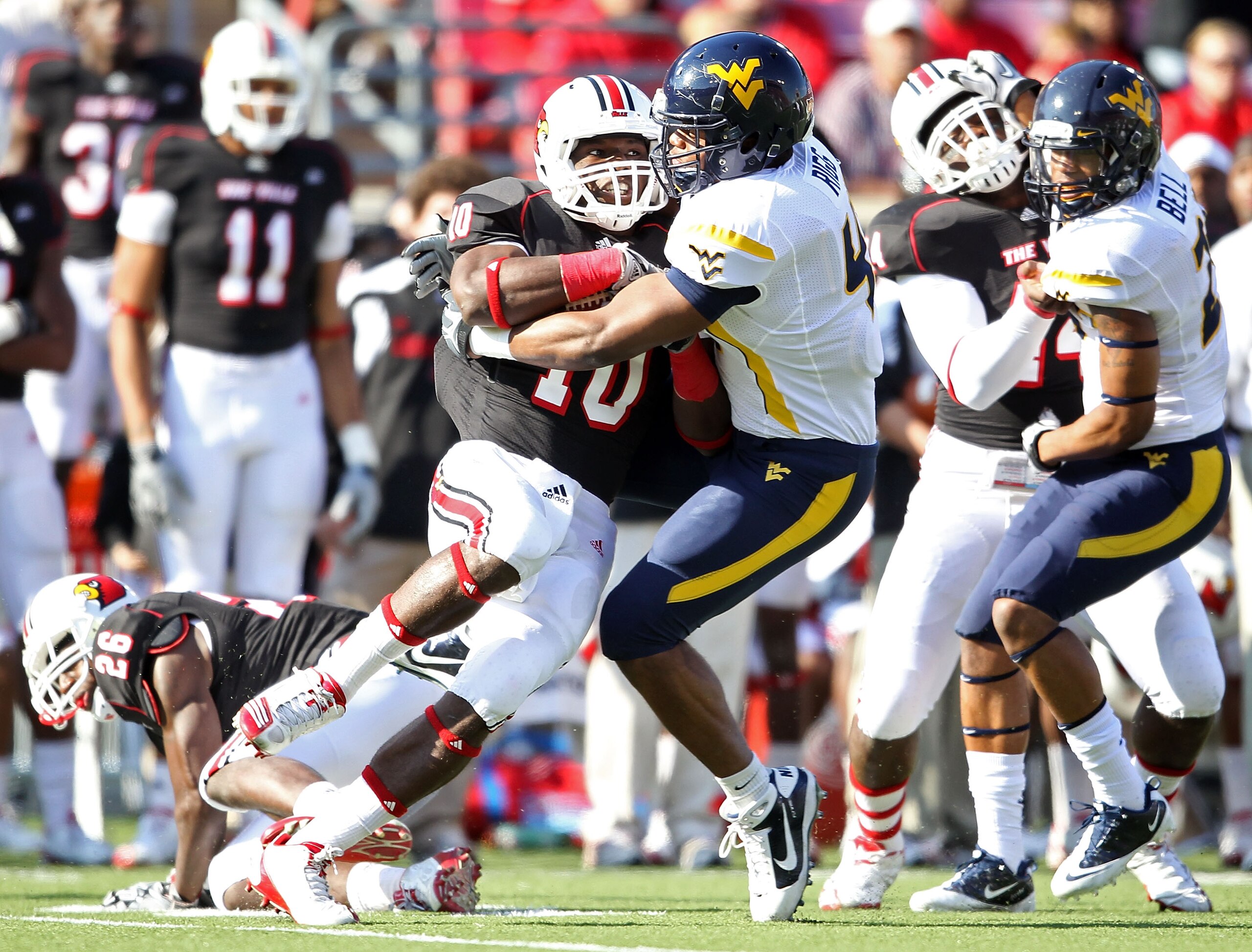 LOUISVILLE, KY - NOVEMBER 20: Dominique Brown #10 of the Louisville Cardinals is tackled by Doug Rigg #47 of the West Virginia Mountaineers during the game at Papa John's Cardinal Stadium on November 20, 2010 in Louisville, Kentucky. (Photo by Andy Lyon LOUISVILLE, KY - NOVEMBER 20: Dominique Brown #10 of the Louisville Cardinals is tackled by Doug Rigg #47 of the West Virginia Mountaineers during the game at Papa John's Cardinal Stadium on November 20, 2010 in Louisville, Kentucky. (Photo by Andy Lyon