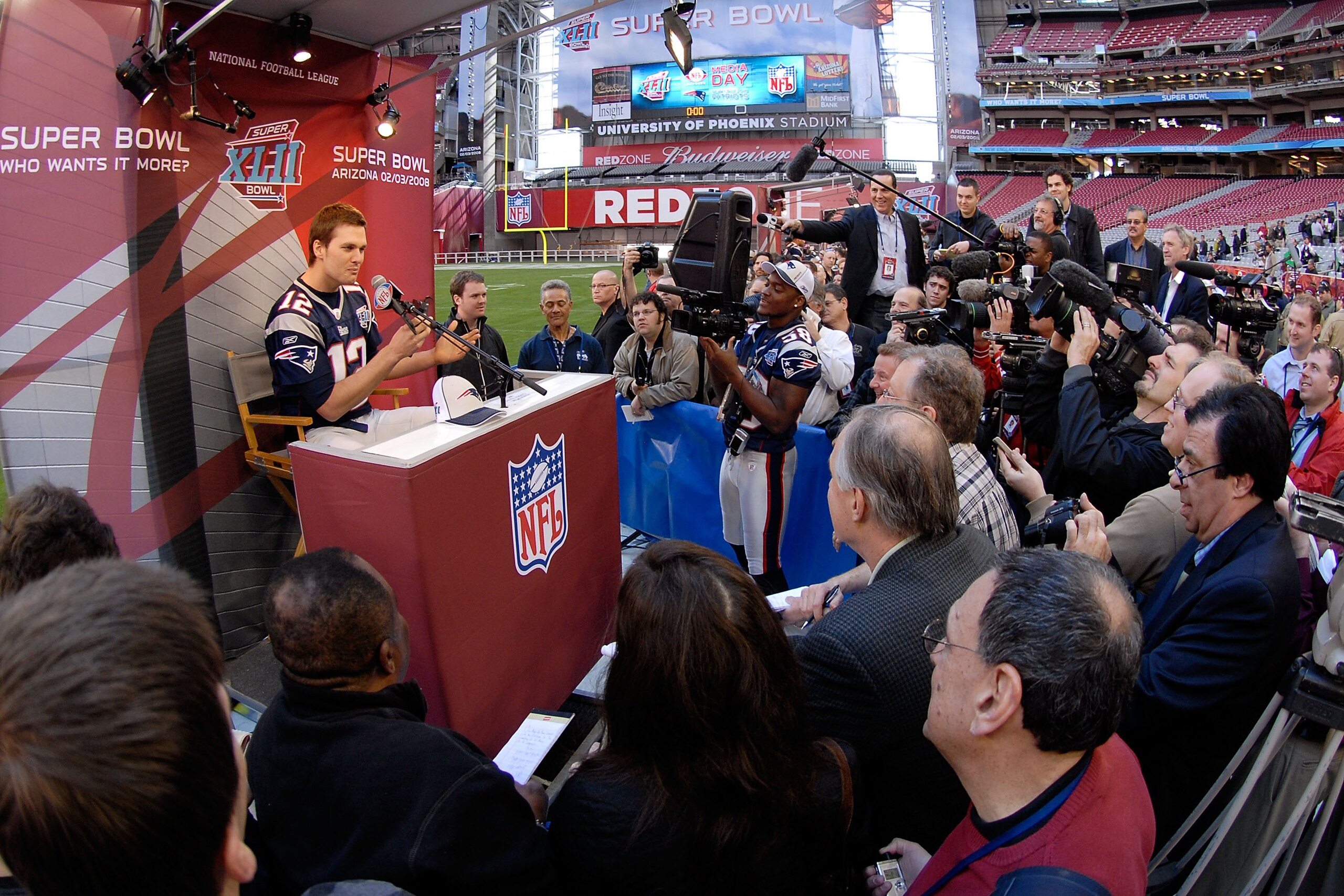 GLENDALE, AZ - JANUARY 29:  Quarterback Tom Brady #12 of the New England Patriots speaks while teammate Pierre Woods #58 of the Patriots records Brady during Patriots media day for Super Bowl XLII at University of Phoenix Stadium on January 29, 2008 in Gl