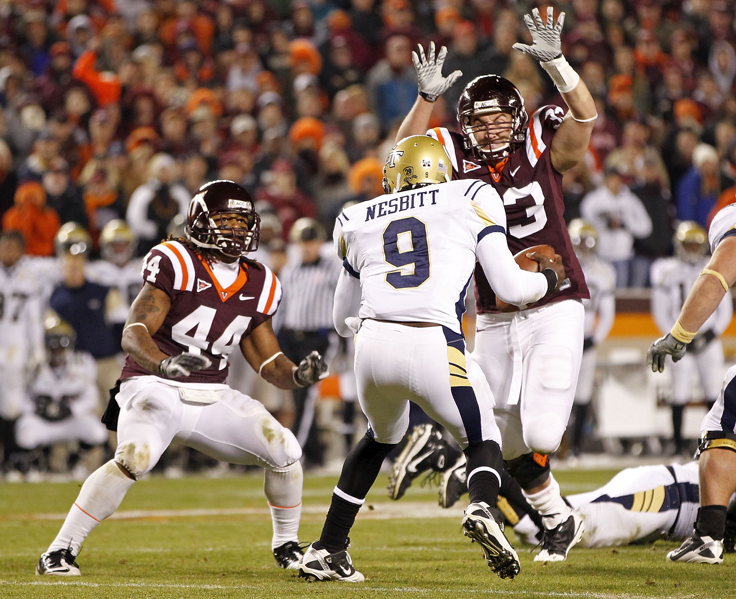 BLACKSBURG, VA - NOVEMBER 04: Quarterback Joshua Nesbitt #9 of the Georgia Tech Yellow Jackets runs with the ball as linebacker Lyndell Gibson #44 of the Virginia Tech Hokies and defensive end Chris Drager #33 of the Virginia Tech Hokies defend at Lane St