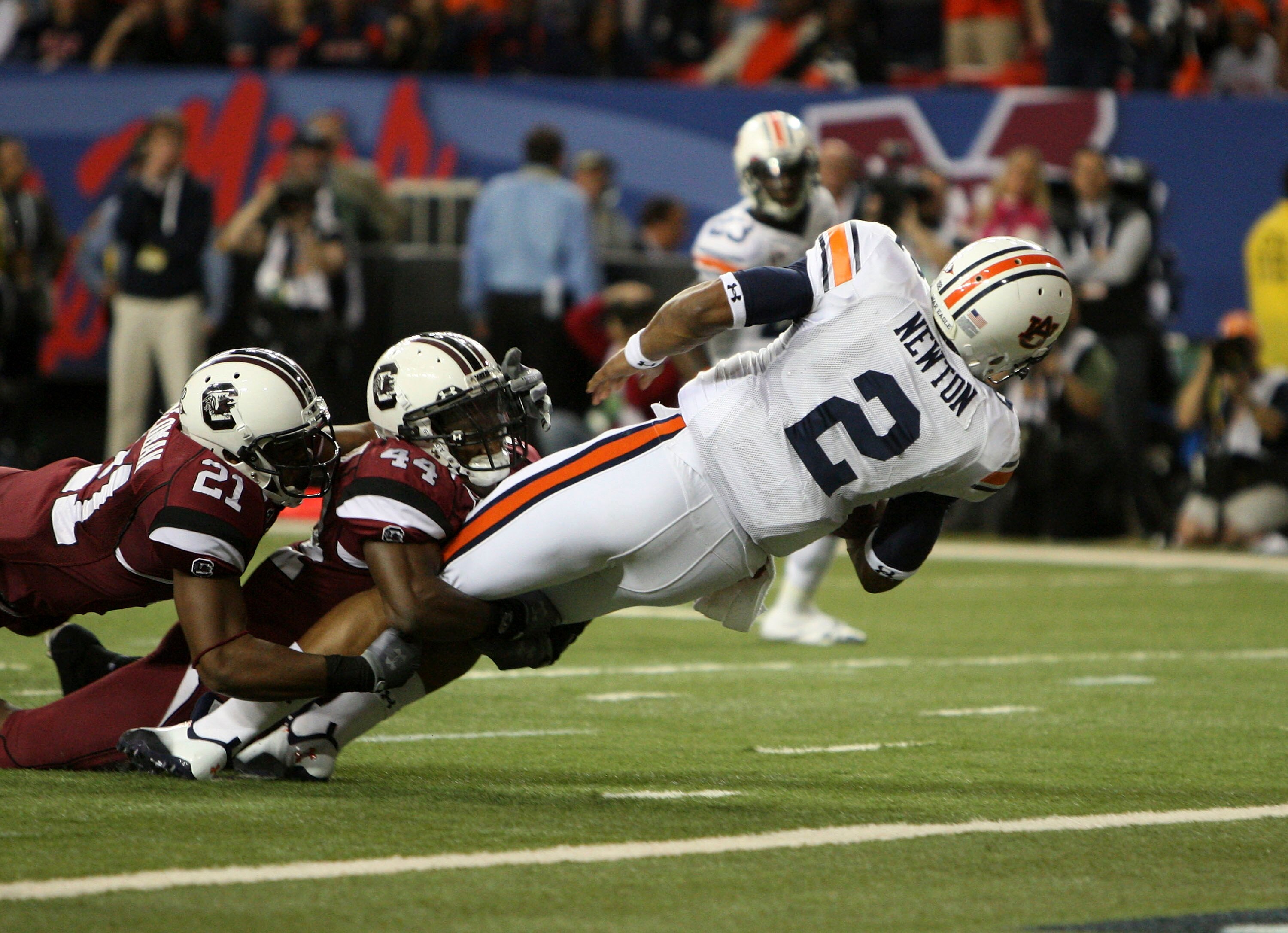 ATLANTA - DECEMBER 4:  Quarterback Cam Newton #2 of the Auburn Tigers dives in for a first quarter touchdown while safety DeVonte Holloman #21 and linebacker Tony Straughter #44 of the South Carolina Gamecocks try to stop him during the 2010 SEC Champions