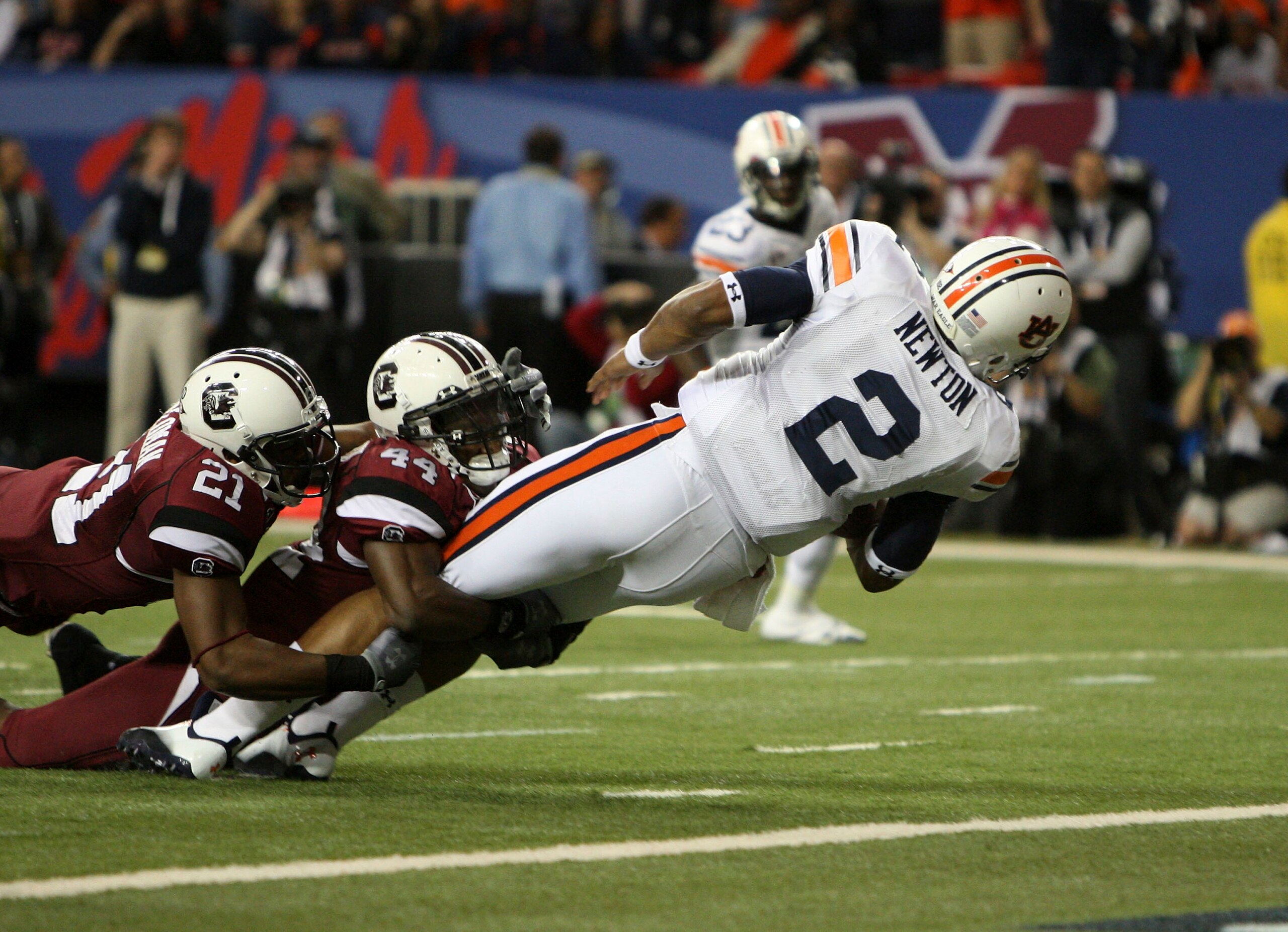 ATLANTA - DECEMBER 4:  Quarterback Cam Newton #2 of the Auburn Tigers dives in for a first quarter touchdown while safety DeVonte Holloman #21 and linebacker Tony Straughter #44 of the South Carolina Gamecocks try to stop him during the 2010 SEC Champions