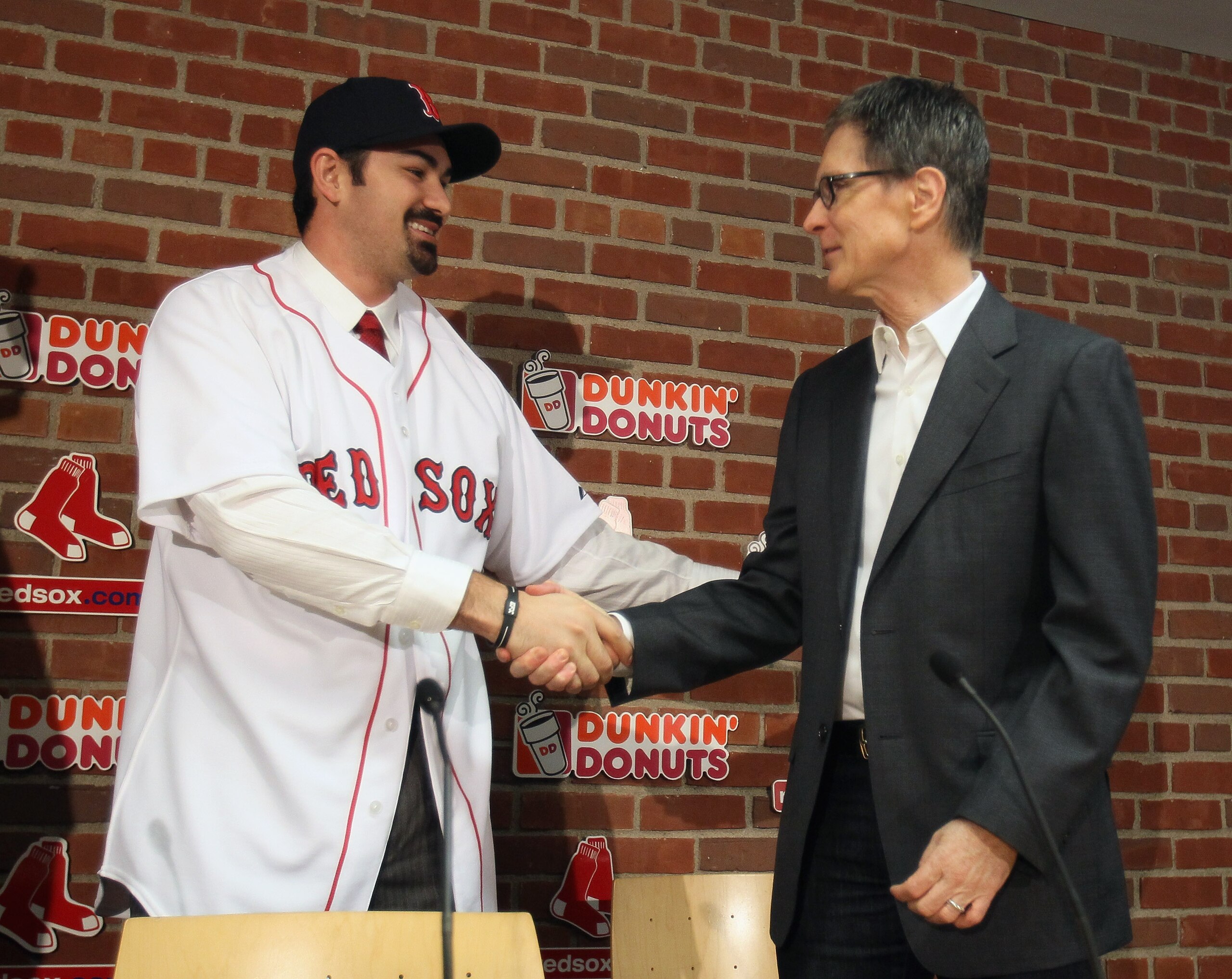 BOSTON, MA - DECEMBER 06:  Adrian Gonzalez (L) shakes hands with principle owner John Henry during a press conference announcing that he signed with the Boston Red Sox on December 6,  2010 at Fenway Park in Boston, Massachusetts.  (Photo by Elsa/Getty Ima