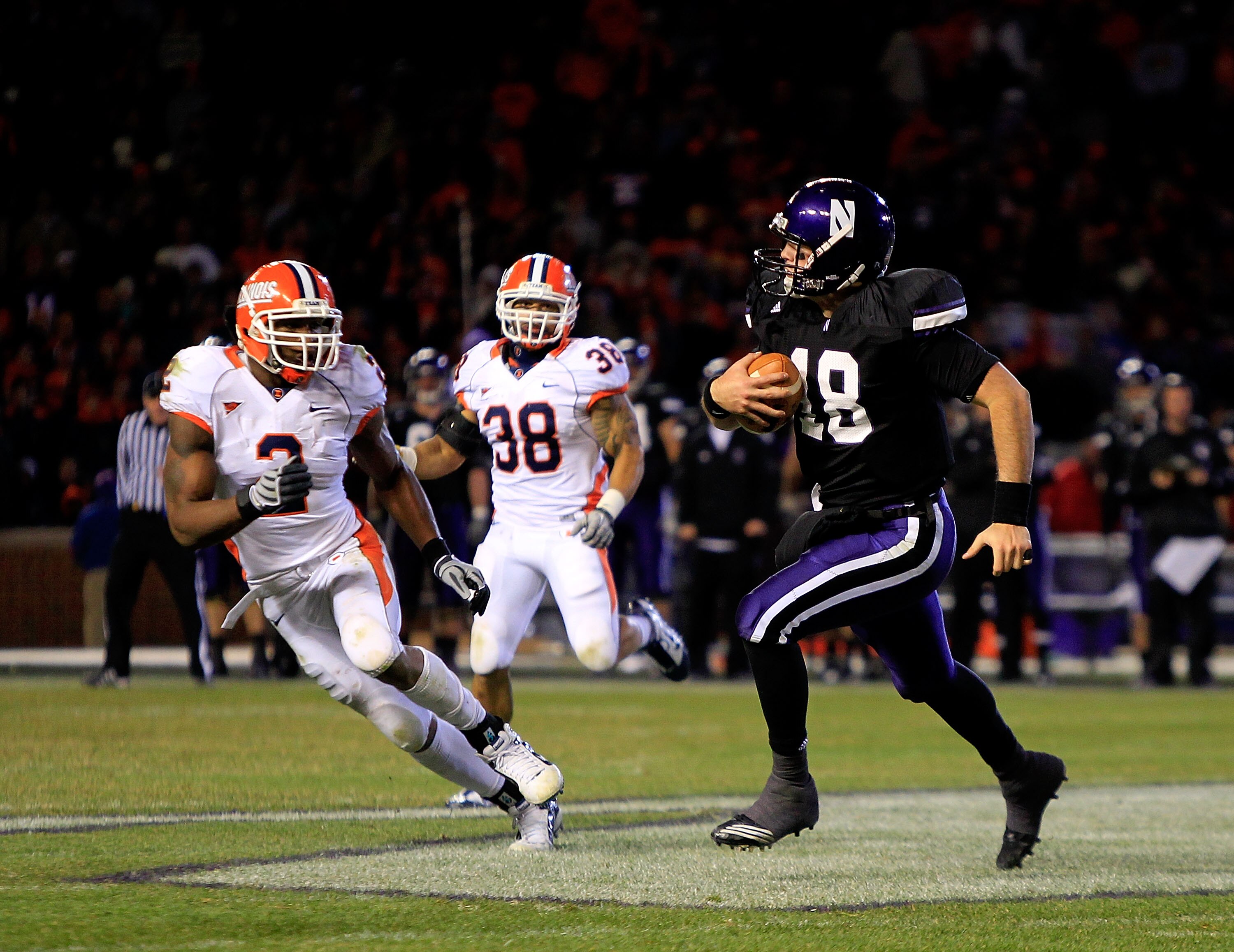 CHICAGO - NOVEMBER 20: Evan Watkins #18 of the Northwestern Wildcats runs for a first down pursued by Travon Wilson #3 and Ian Thomas #38 of the Illinois Fighting Illini during a game played at Wrigley Field on November 20, 2010 in Chicago, Illinois. Illi