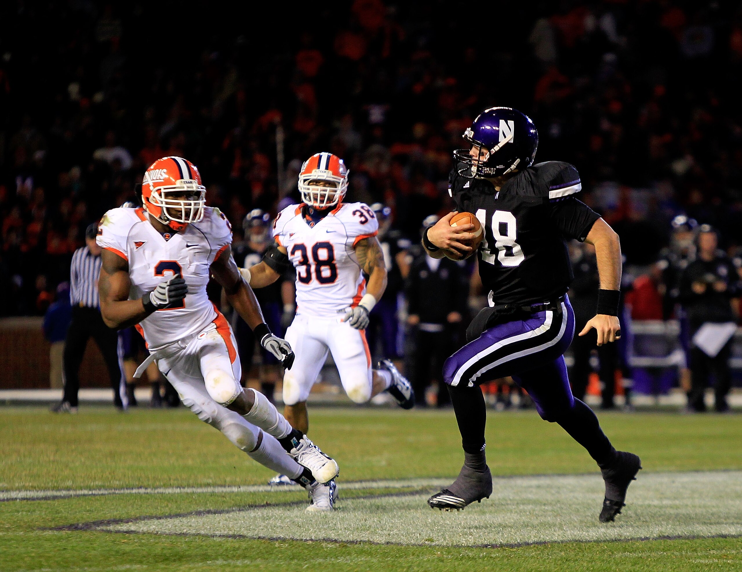 CHICAGO - NOVEMBER 20: Evan Watkins #18 of the Northwestern Wildcats runs for a first down pursued by Travon Wilson #3 and Ian Thomas #38 of the Illinois Fighting Illini during a game played at Wrigley Field on November 20, 2010 in Chicago, Illinois. Illi