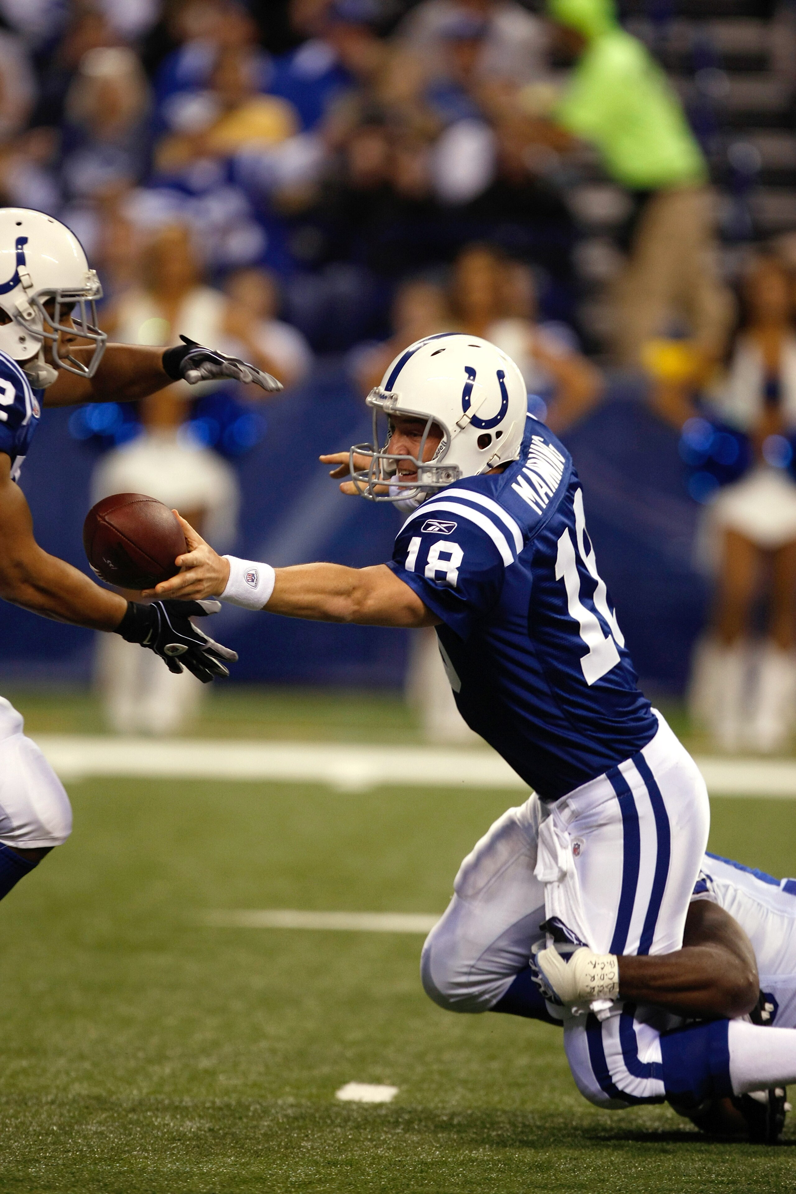 INDIANAPOLIS, IN - DECEMBER 05: Peyton Manning #18 of the Indianapolis Colts hands off as he trips against the Dallas Cowboys at Lucas Oil Stadium on December 5, 2010 in Indianapolis, Indiana.  (Photo by Scott Boehm/Getty Images)