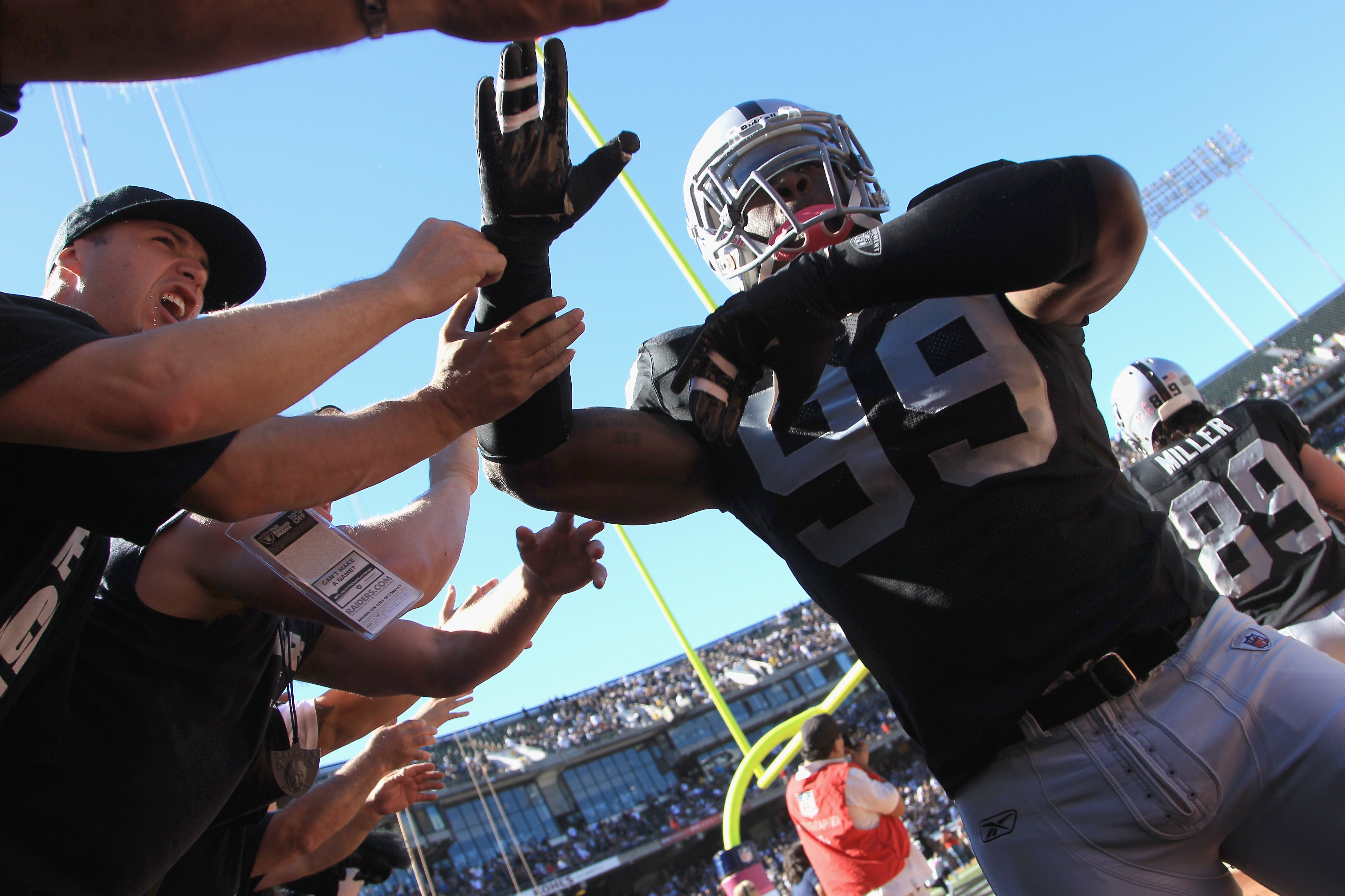 OAKLAND, CA - OCTOBER 10: Lamarr Houston #99 of the Oakland Raiders high fives fans before their game against the San Diego Chargers at Oakland-Alameda County Coliseum on October 10, 2010 in Oakland, California. (Photo by Ezra Shaw/Getty Images) OAKLAND, CA - OCTOBER 10: Lamarr Houston #99 of the Oakland Raiders high fives fans before their game against the San Diego Chargers at Oakland-Alameda County Coliseum on October 10, 2010 in Oakland, California. (Photo by Ezra Shaw/Getty Images)