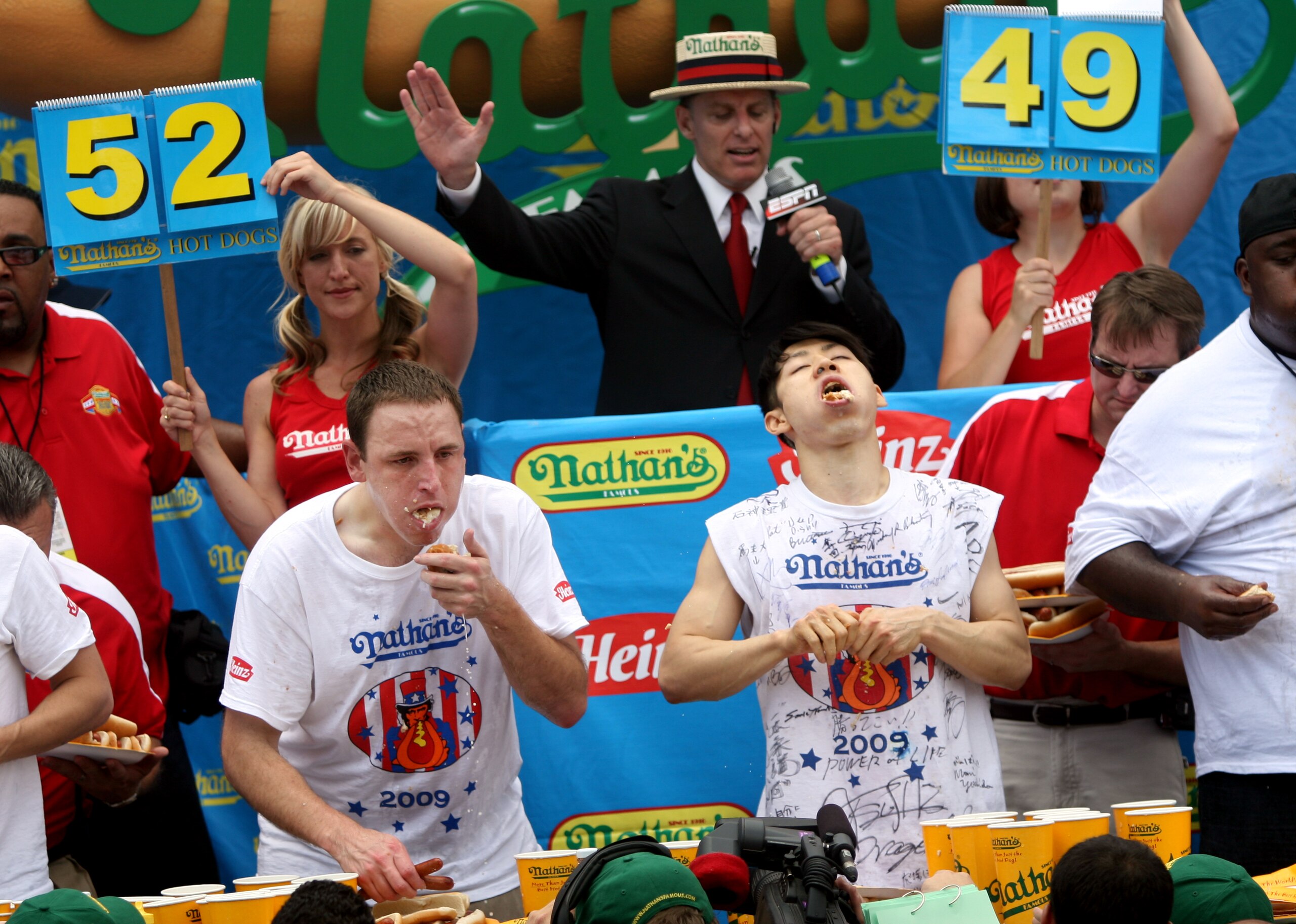 NEW YORK - JULY 4:  Joey Chestnut of San Jose, California (C) and Takeru Kobayashi of Nagano, Japan (R) stuff hot dogs into their mouths during Nathan's Famous Fourth of July hot dog eating contest on July 4, 2009 in Coney Island in the Brooklyn borough o