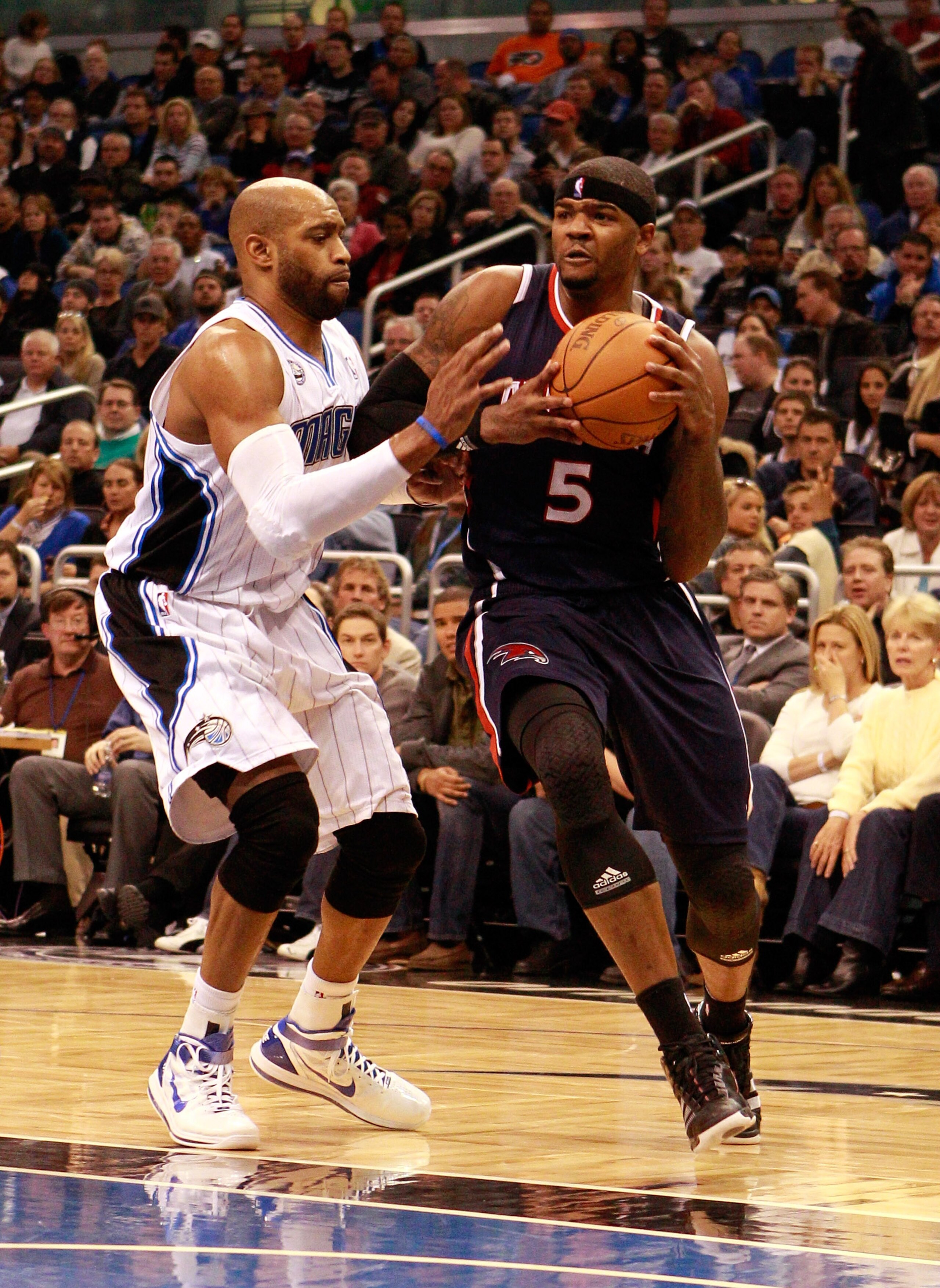 ORLANDO, FL - DECEMBER 06:  Josh Smith #5 of the Atlanta Hawks drives against Vince Carter#15 of the Orlando Magic during the game at Amway Arena on December 6, 2010 in Orlando, Florida. NOTE TO USER: User expressly acknowledges and agrees that, by downlo