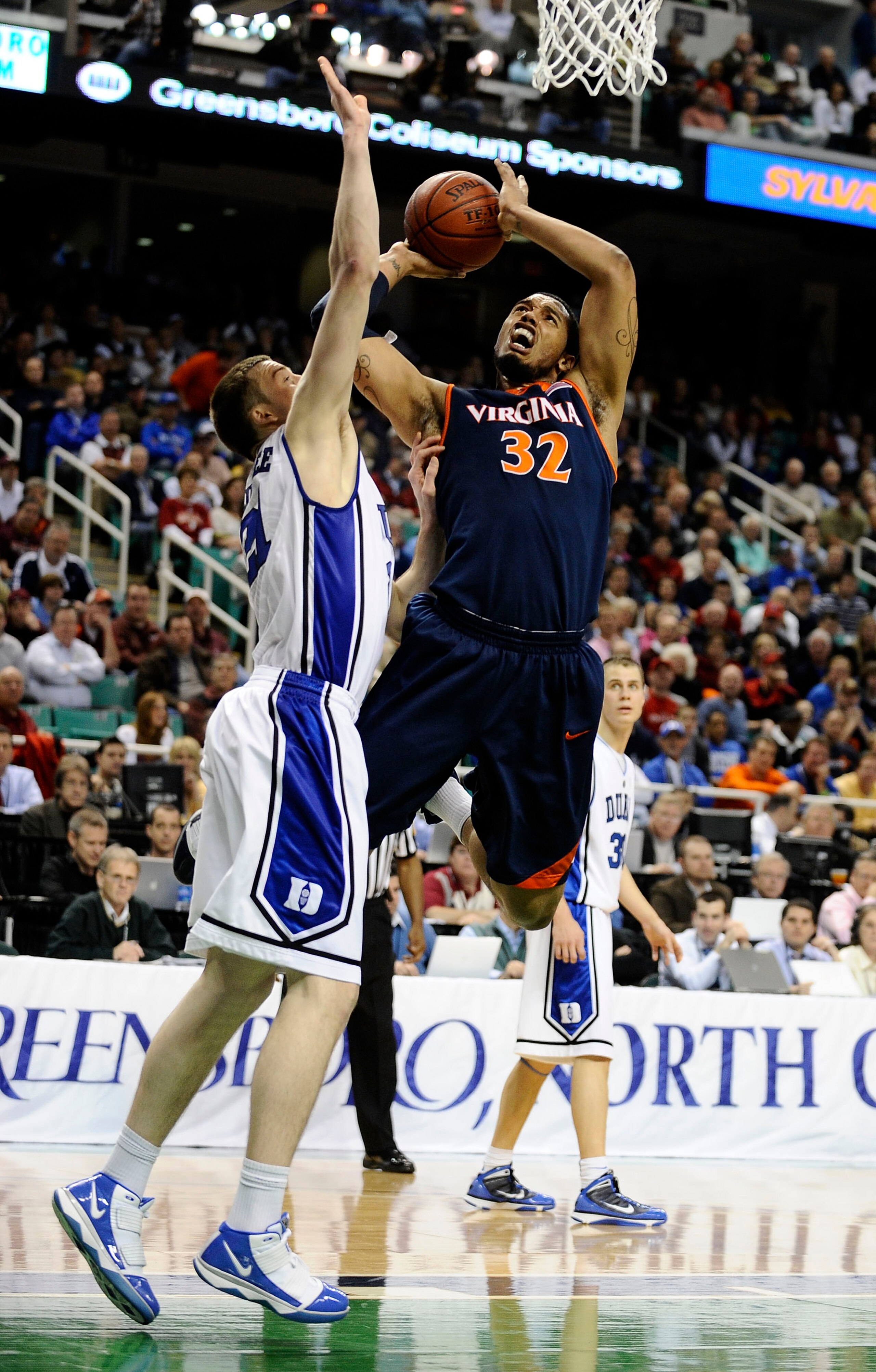 GREENSBORO, NC - MARCH 12:  MIles Plumlee #21 of the Duke Blue Devils guards Mike Scott #32  of the University of Virginia Cavaliers in their quarterfinal game in the 2010 ACC Men's Basketball Tournament at the Greensboro Coliseum on March 12, 2010 in Gre