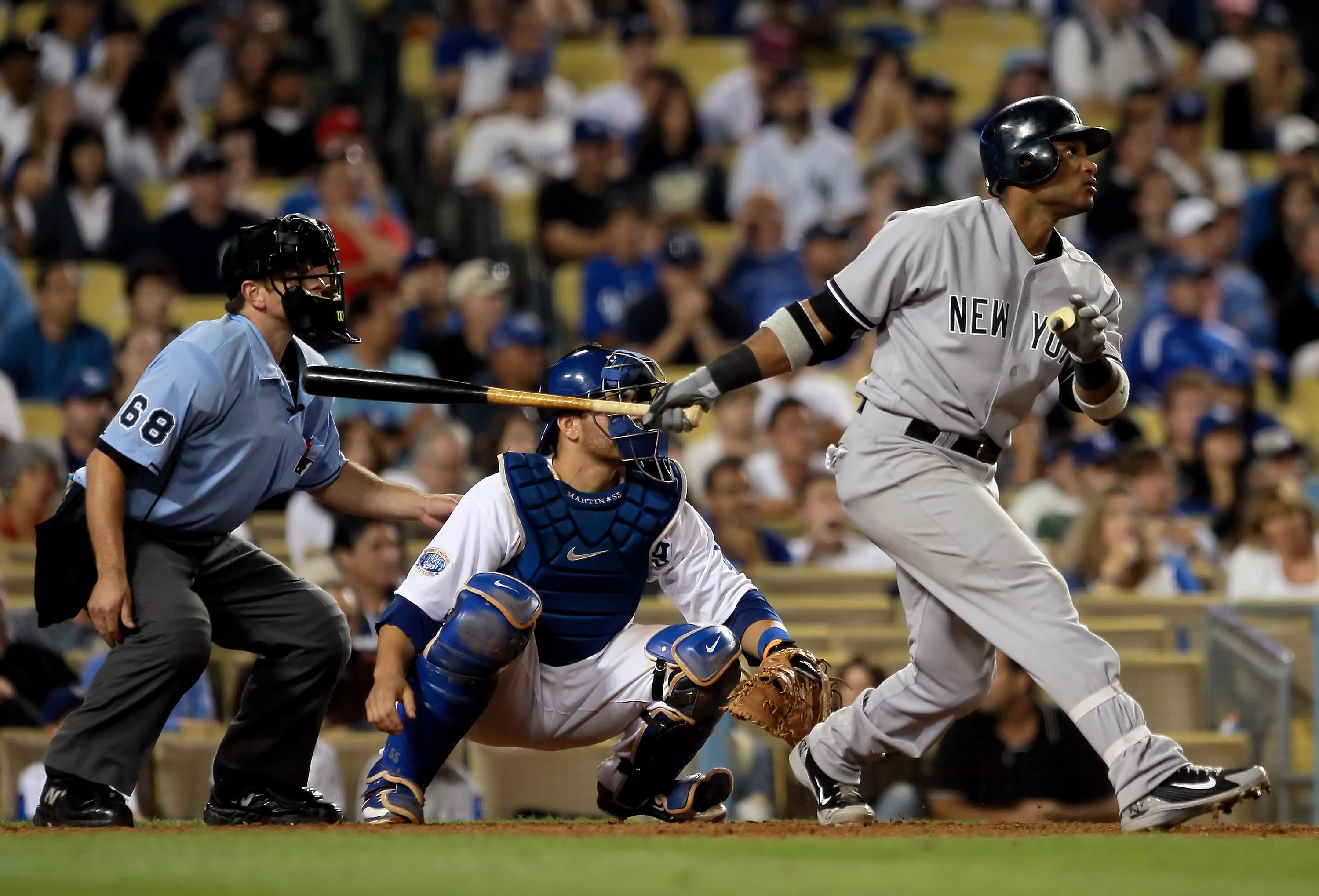 LOS ANGELES, CA - JUNE 27:  Robinson Cano #24 of the New York Yankees hits a two-run homerun in the tenth inning as catcher Russell Martin #55 of the Los Angeles Dodgers looks on during an interleague at Dodger Stadium on June 27, 2010 in Los Angeles, Cal