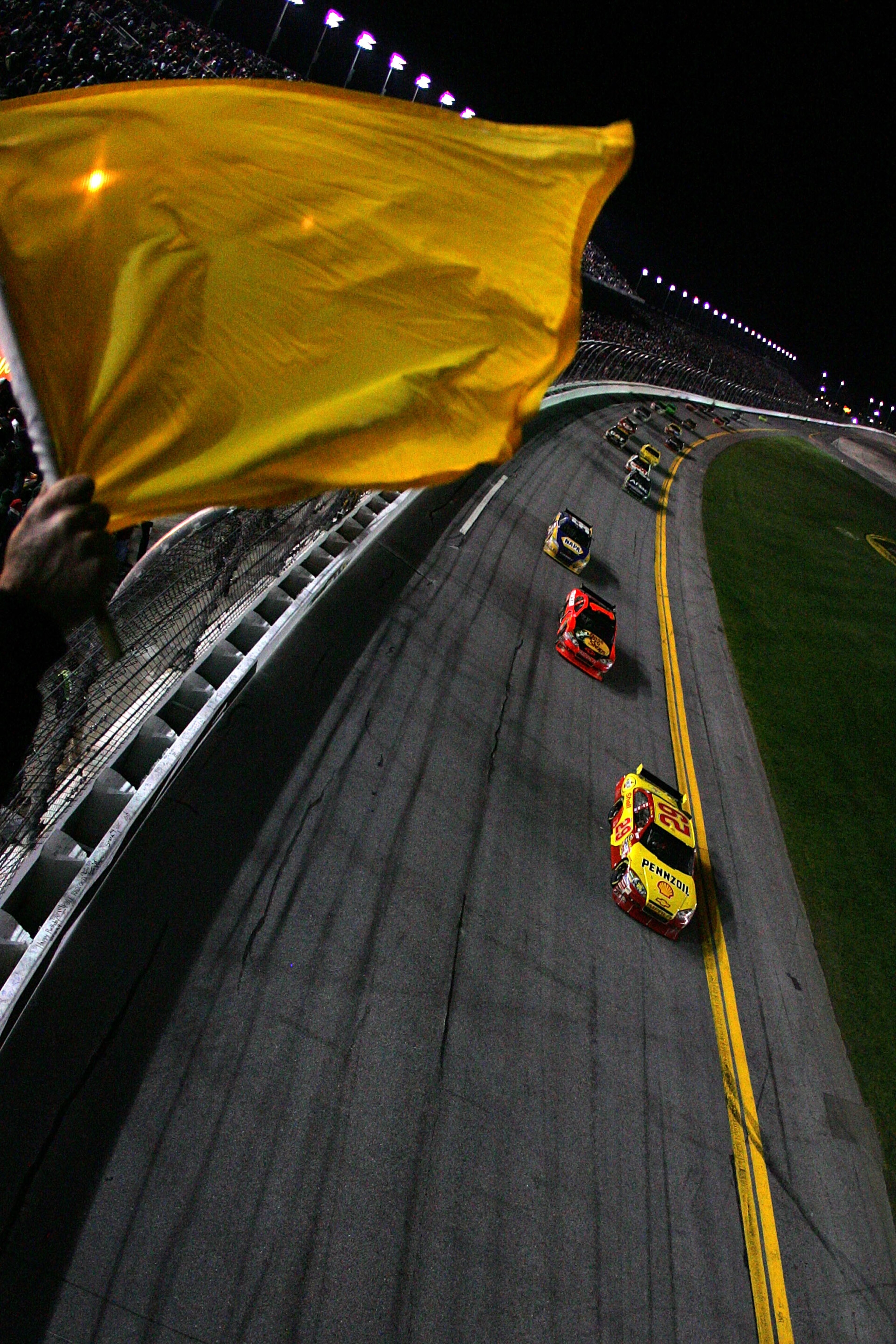 DAYTONA BEACH, FL - FEBRUARY 14:  Officials wave a yellow caution flag as Kevin Harvick, driver of the #29 Shell/Pennzoil Chevrolet, leads a group of cars late in the NASCAR Sprint Cup Series Daytona 500 at Daytona International Speedway on February 14, 2
