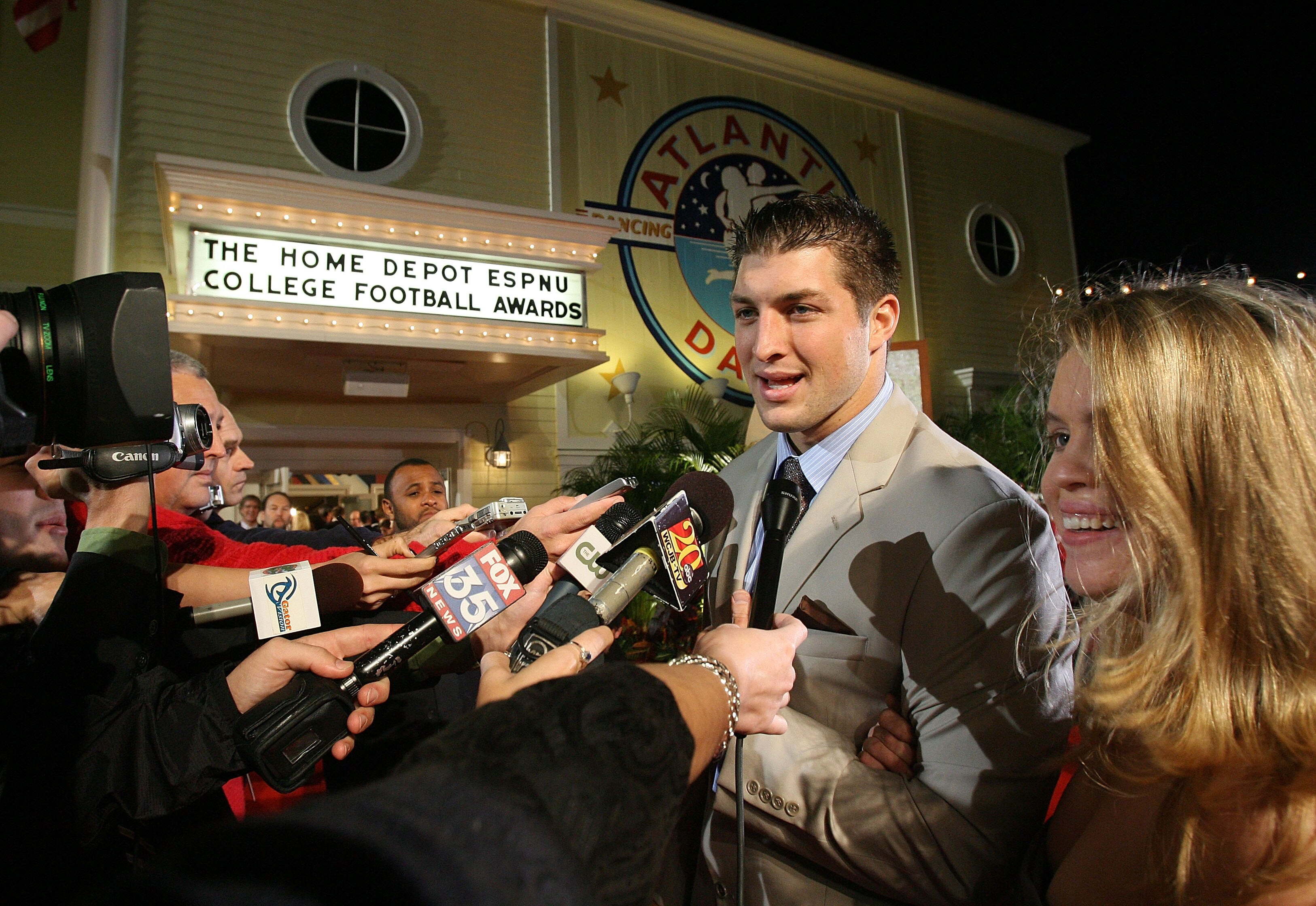 LAKE BUENA VISTA, FL - DECEMBER 10:  Quarterback Tim Tebow of the University of Florida Gators talks with media representatives as he arrives with friend Kelly Faughnan on the red carpet before the Home Depot ESPNU College Football Awards at the Disney Bo