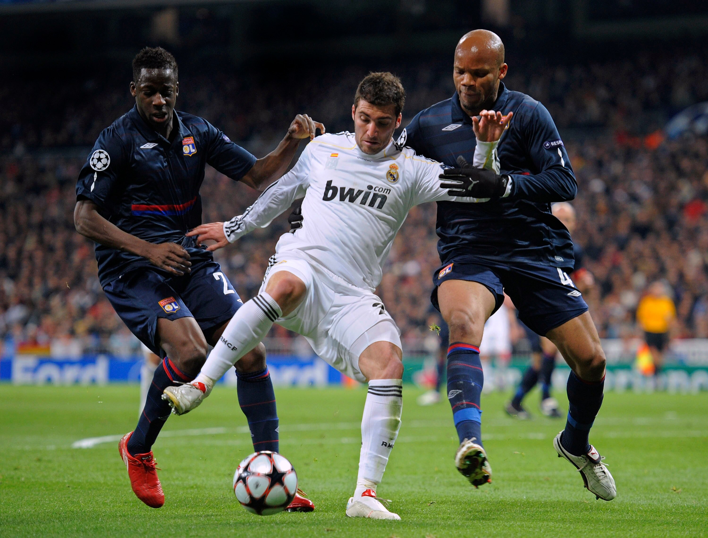 MADRID, SPAIN - MARCH 10: Gonzalo Higuain (C) of Real Madrid competes for the ball with Jean-Alain Boumsong (R) and  Aly Cissokho of Olympique Lyonnais during the UEFA Champions League round of 16 2nd leg match between  Real Madrid and Olympique Lyonnais