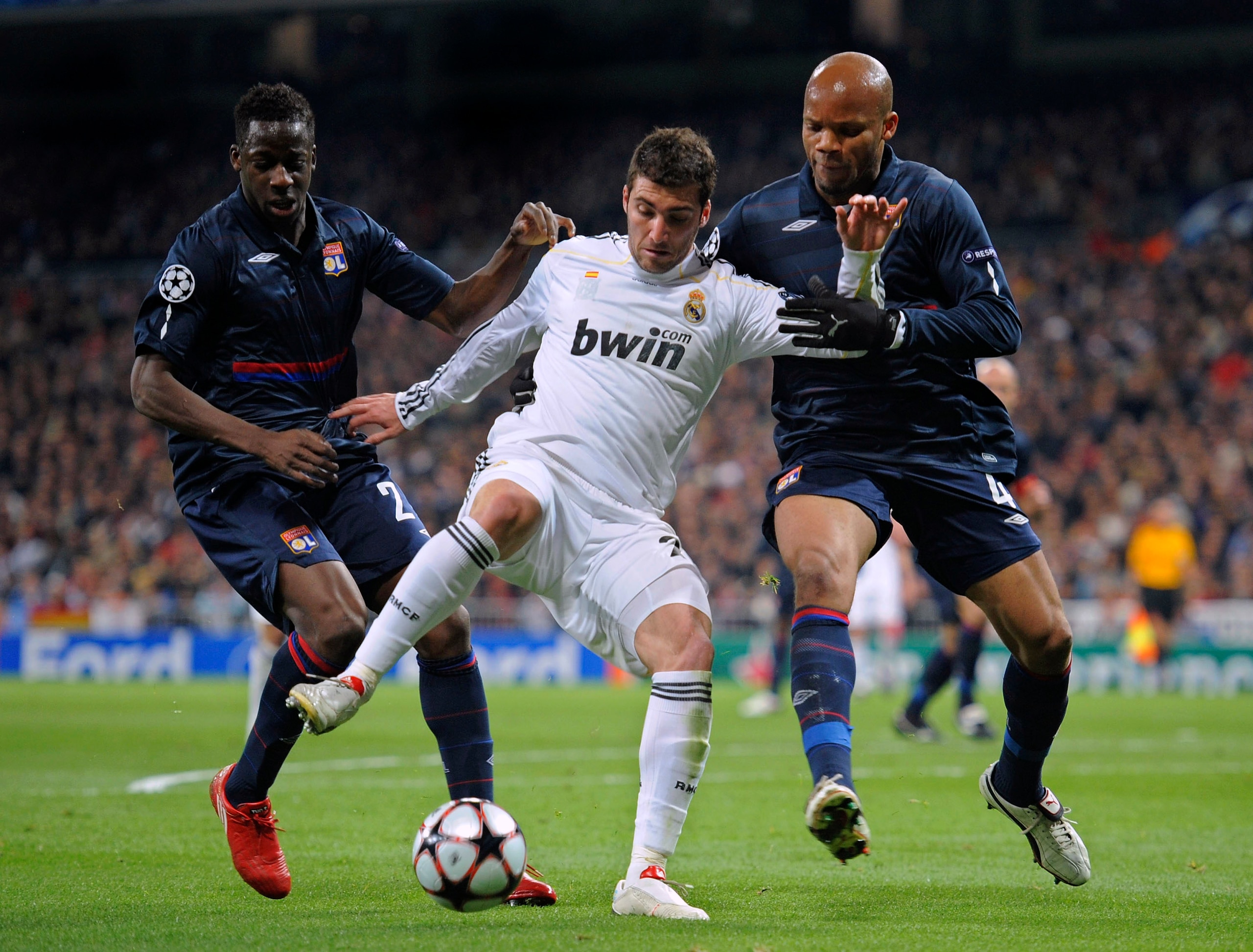 MADRID, SPAIN - MARCH 10: Gonzalo Higuain (C) of Real Madrid competes for the ball with Jean-Alain Boumsong (R) and  Aly Cissokho of Olympique Lyonnais during the UEFA Champions League round of 16 2nd leg match between  Real Madrid and Olympique Lyonnais