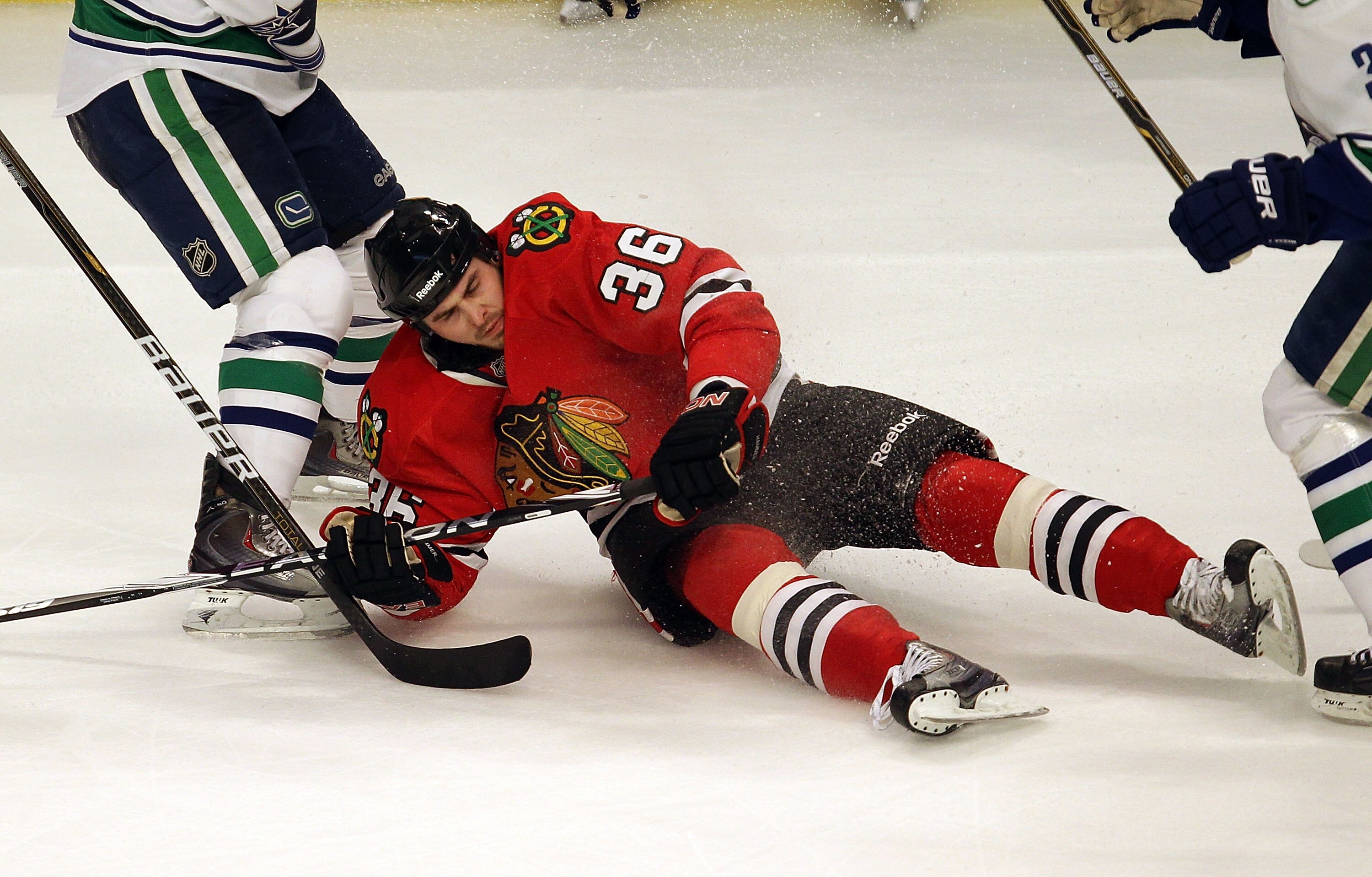 CHICAGO - DECEMBER 03: Dave Bolland #36 of the Chicago Blackhawks falls to the ice between two  Vancouver Canuck defenders at the United Center on December 3, 2010 in Chicago, Illinois. The Canucks defeated the Blackhawks 3-0. (Photo by Jonathan Daniel/Ge