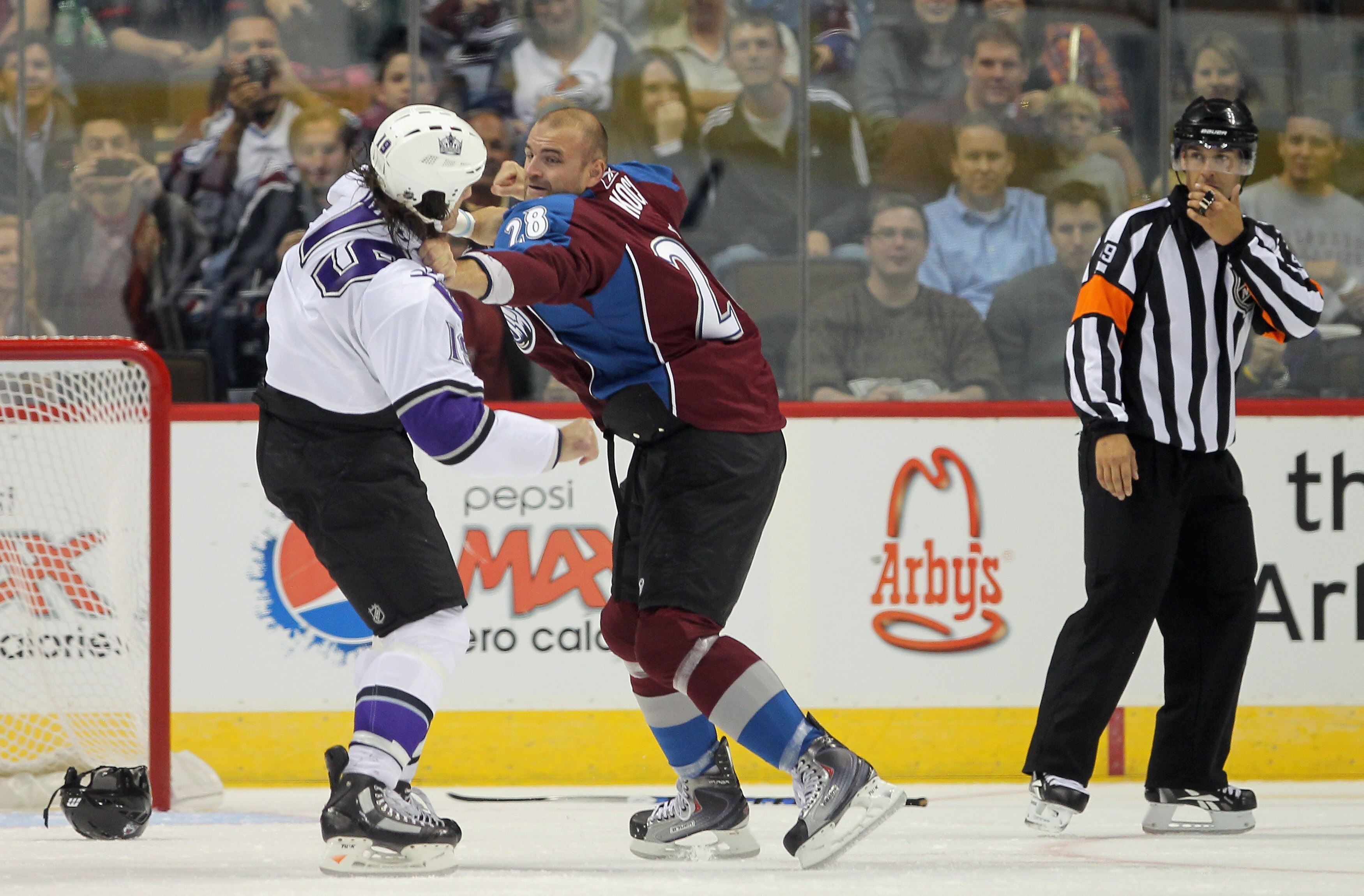 DENVER - SEPTEMBER 22:  John Zeiler #13 of the Los Angeles Kings and David Koci #28 of the Colorado Avalanche engage in a fight as referee Ghislain Hebert watches during preseason NHL action at the Pepsi Center on September 22, 2010 in Denver, Colorado. T