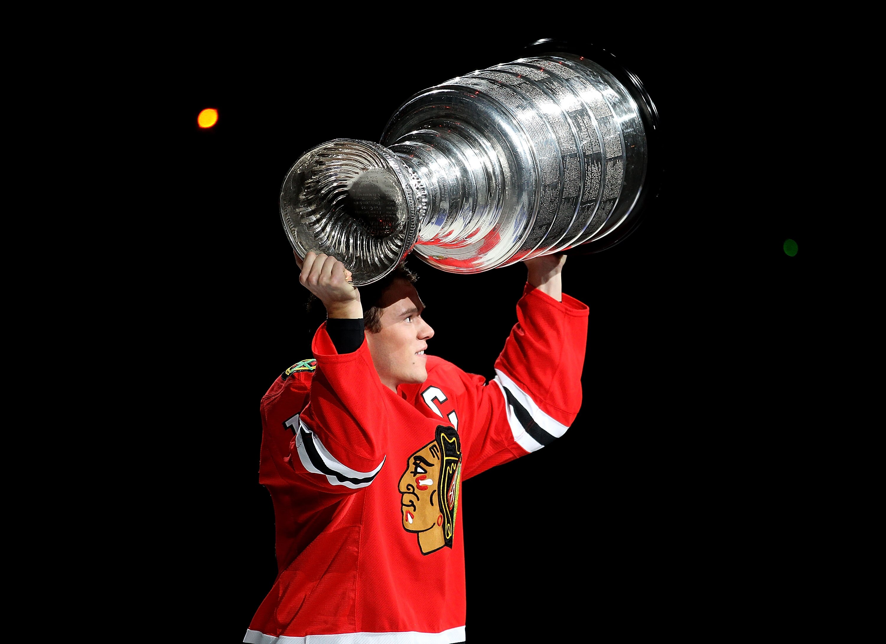 CHICAGO - OCTOBER 09: Jonathan Toews #19 of the Chicago Blackhawks carries the Stanley Cup trophy across the ice in a ceremony before the Blackhawks season home opening game against the Detroit Red Wings at the United Center on October 9, 2010 in Chicago,