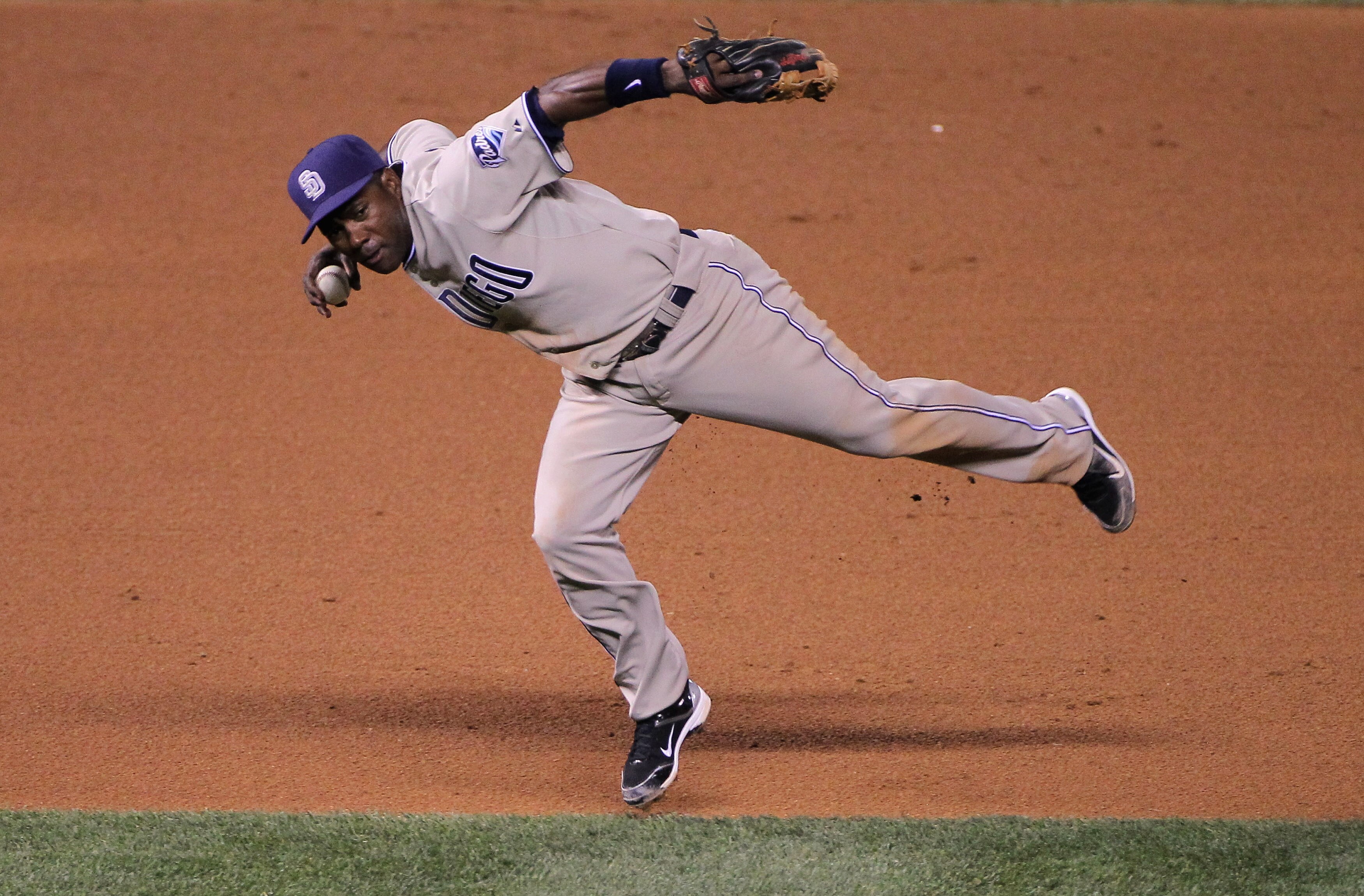 DENVER - SEPTEMBER 14:  Shortstop Miguel Tejada #10 of the San Diego Padres makes a bare handed stop and a late throw as Troy Tulowitzki of the Colorado Rockies is safe with a single on a soft grounder in the fourth inning at Coors Field on September 14,