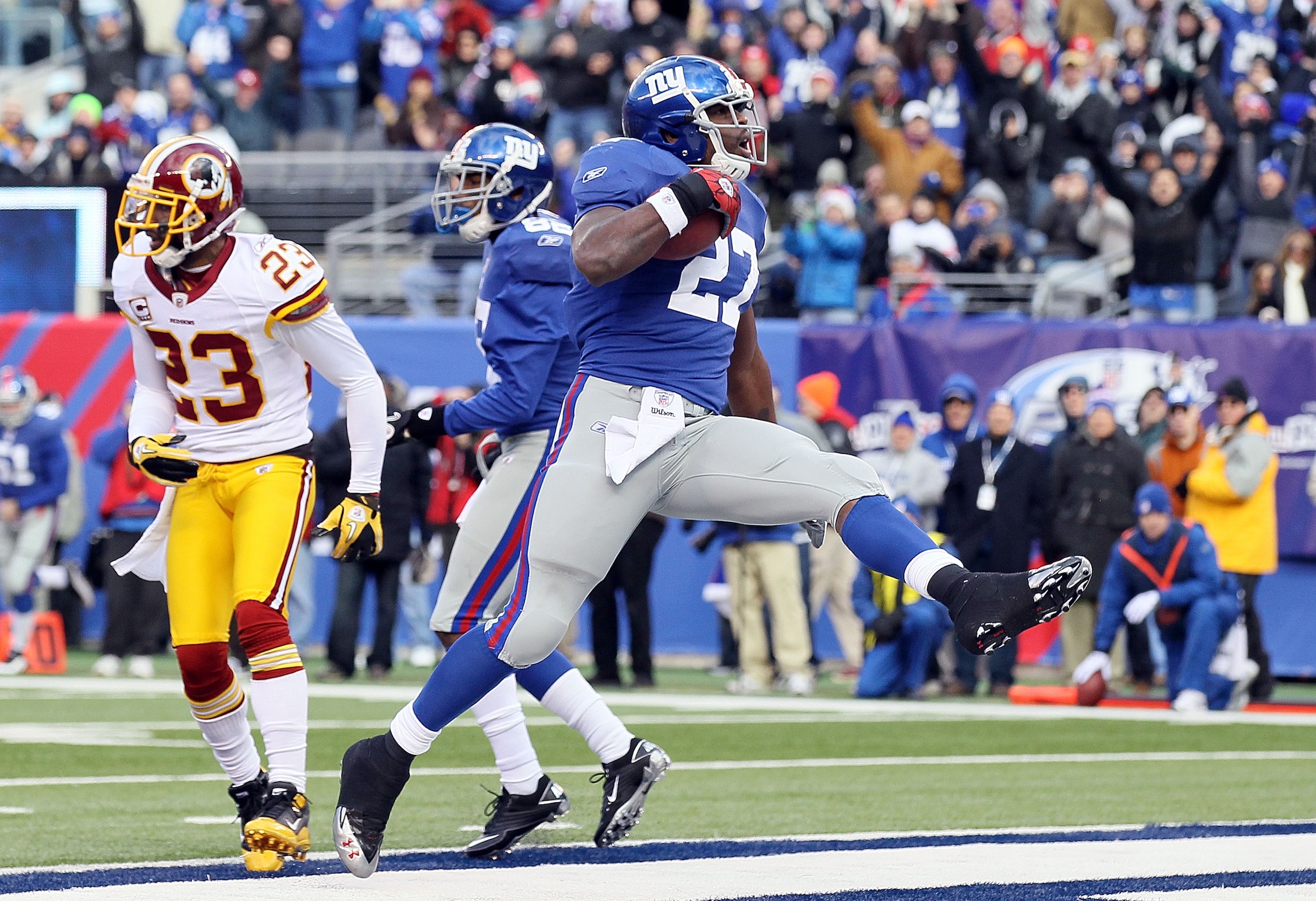EAST RUTHERFORD, NJ - DECEMBER 05:  Brandon Jacobs #27 of the New York Giants carries the ball past DeAngelo Hall #23 of the Washington Redskins for a first quarter touchdown on December 5, 2010 at the New Meadowlands Stadium in East Rutherford, New Jerse