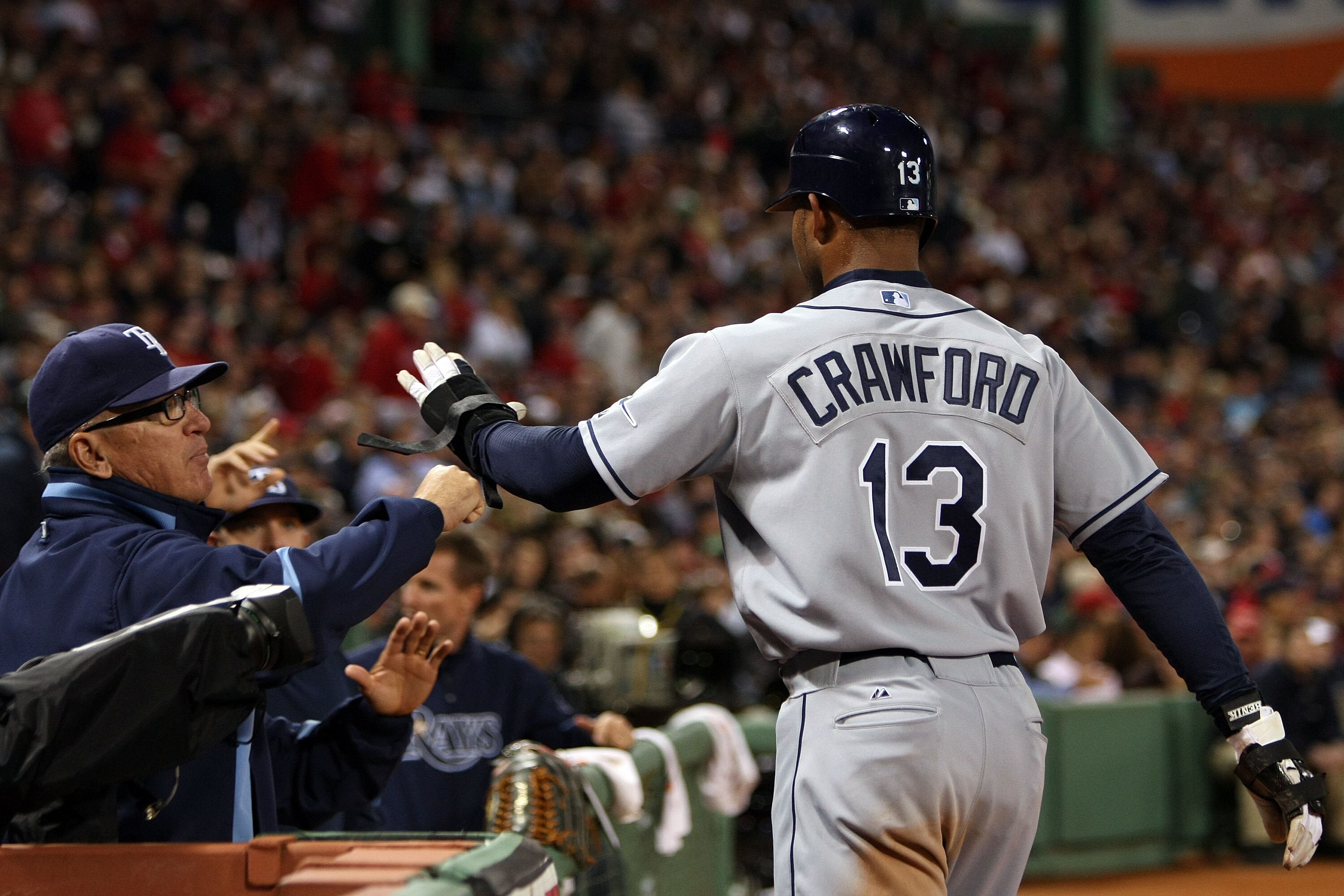 BOSTON - OCTOBER 14:  Manager Joe Maddon of the Tampa Bay Rays congratulates Carl Crawford #13 after scoring during game four of the American League Championship Series against the Boston Red Sox during the 2008 MLB playoffs at Fenway Park on October 14,
