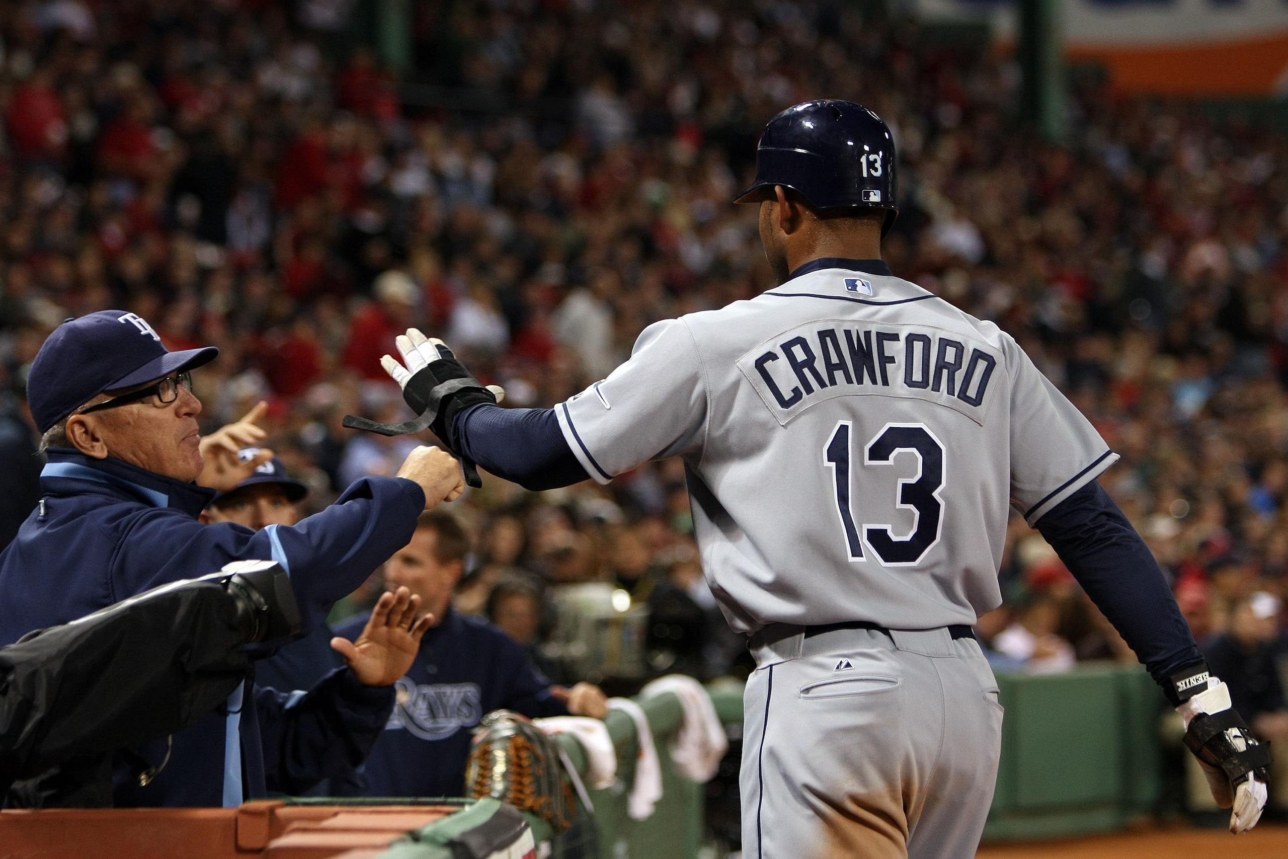 BOSTON - OCTOBER 14:  Manager Joe Maddon of the Tampa Bay Rays congratulates Carl Crawford #13 after scoring during game four of the American League Championship Series against the Boston Red Sox during the 2008 MLB playoffs at Fenway Park on October 14,