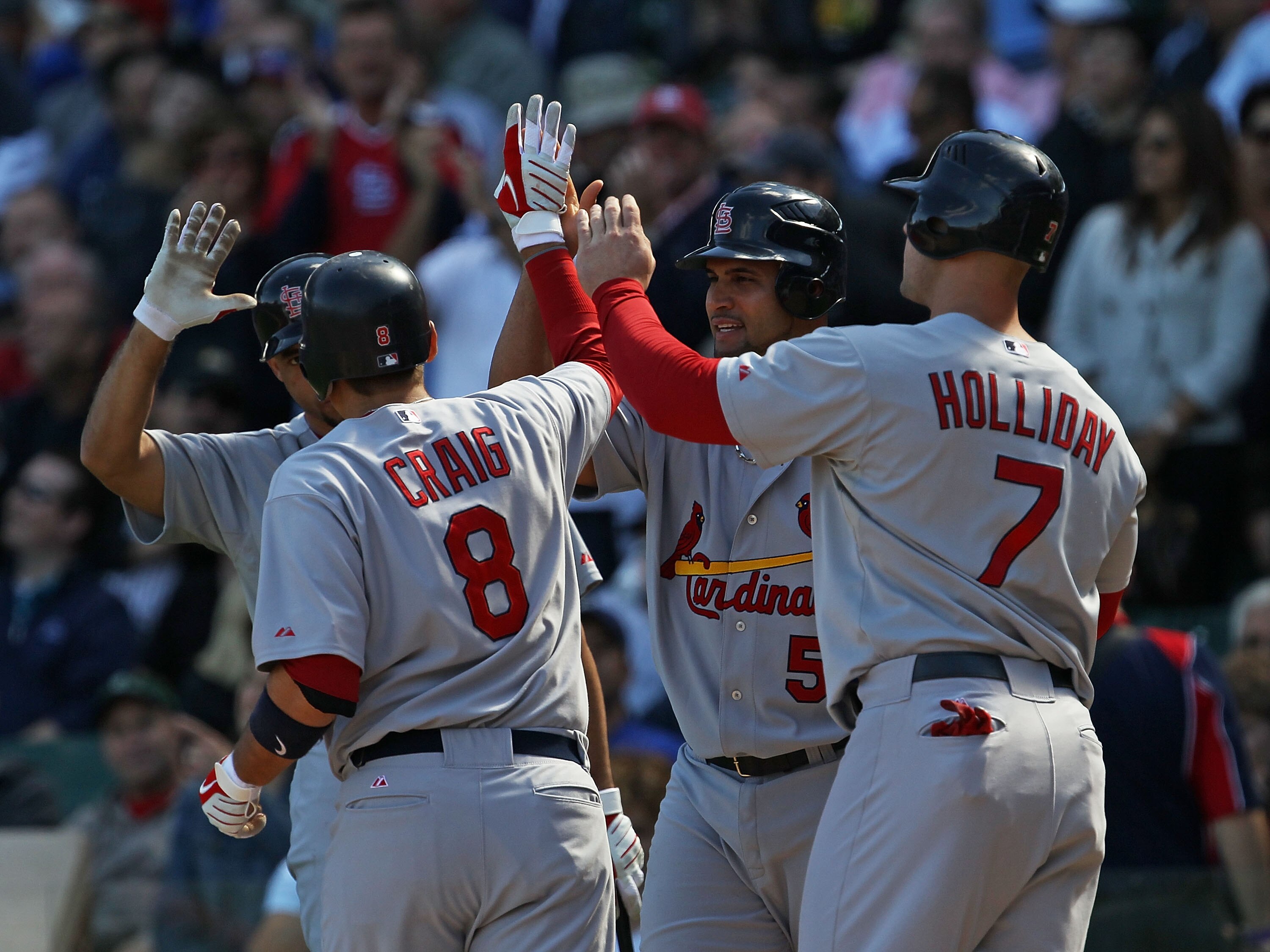 CHICAGO - SEPTEMBER 24: Allen Craig #8 of the St. Louis Cardinals is congratulated by (L-R) Pedro Feliz #77, Albert Pujols #5 and Matt Holliday #7 after hitting a three-run home run in the 1st inning against the Chicago Cubs at Wrigley Field on September 